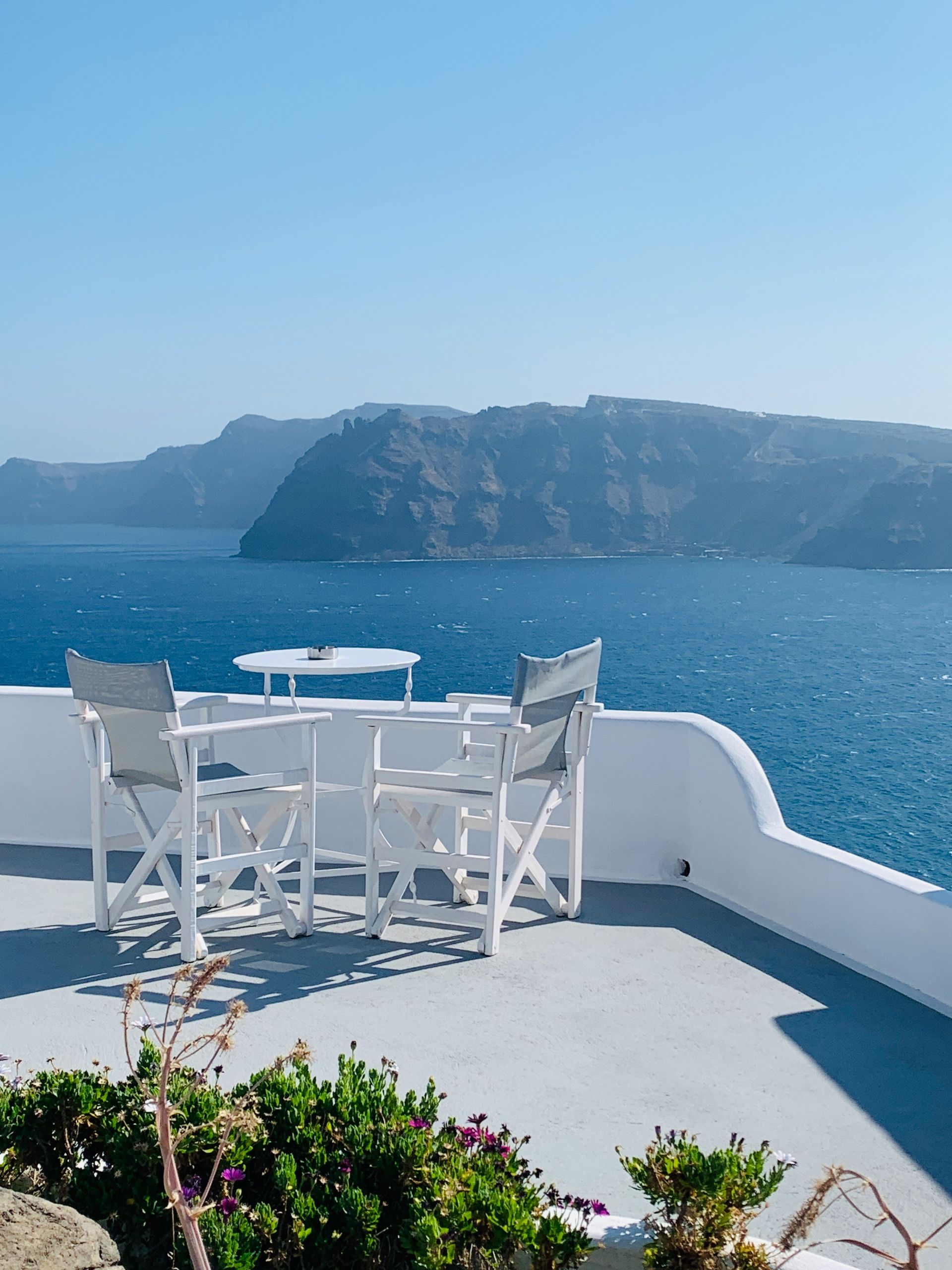 A table and chairs on a balcony overlooking the ocean in Santorini, Greece.