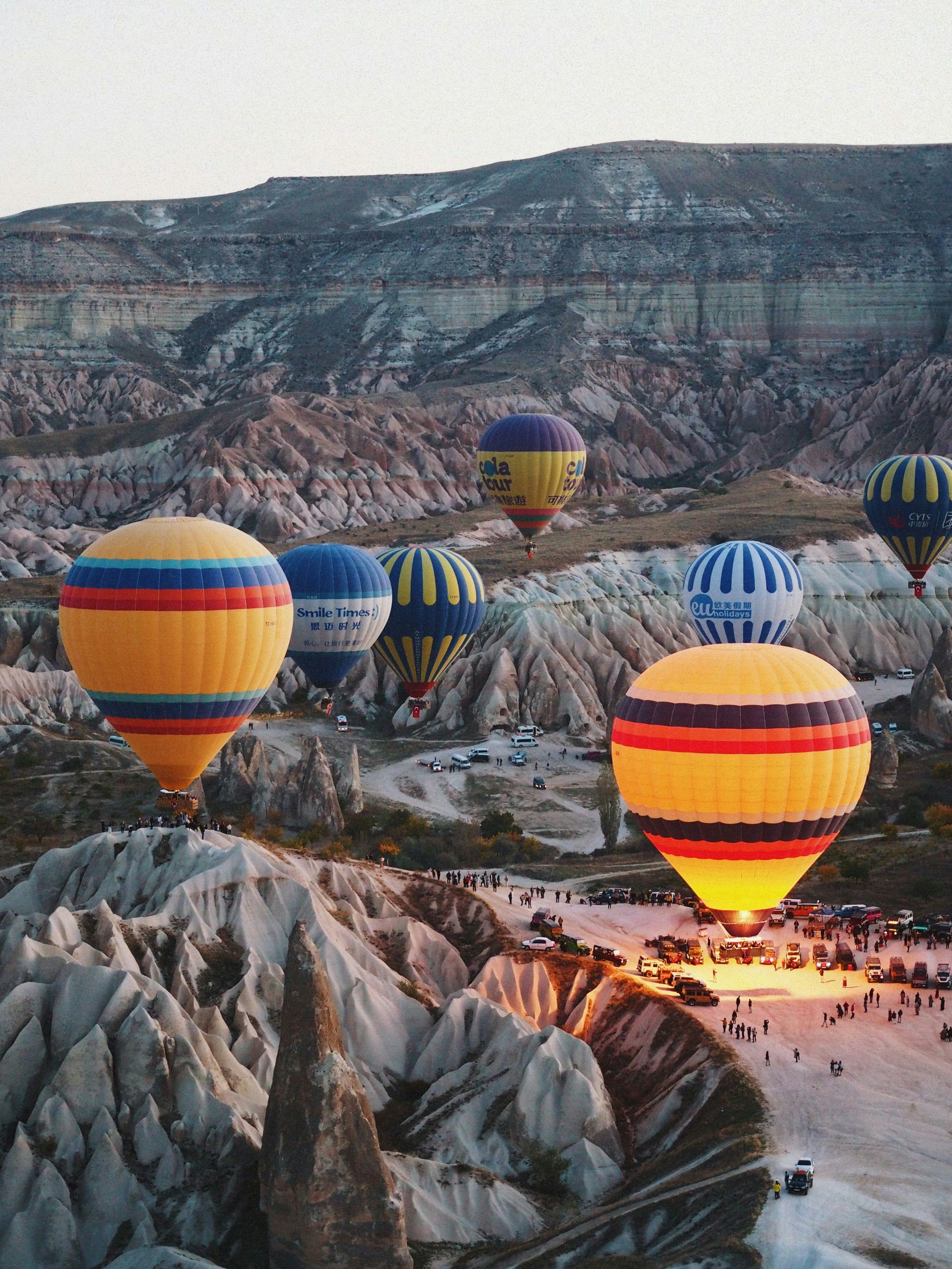 Hot air balloons over Cappadocia rock formations at sunrise.