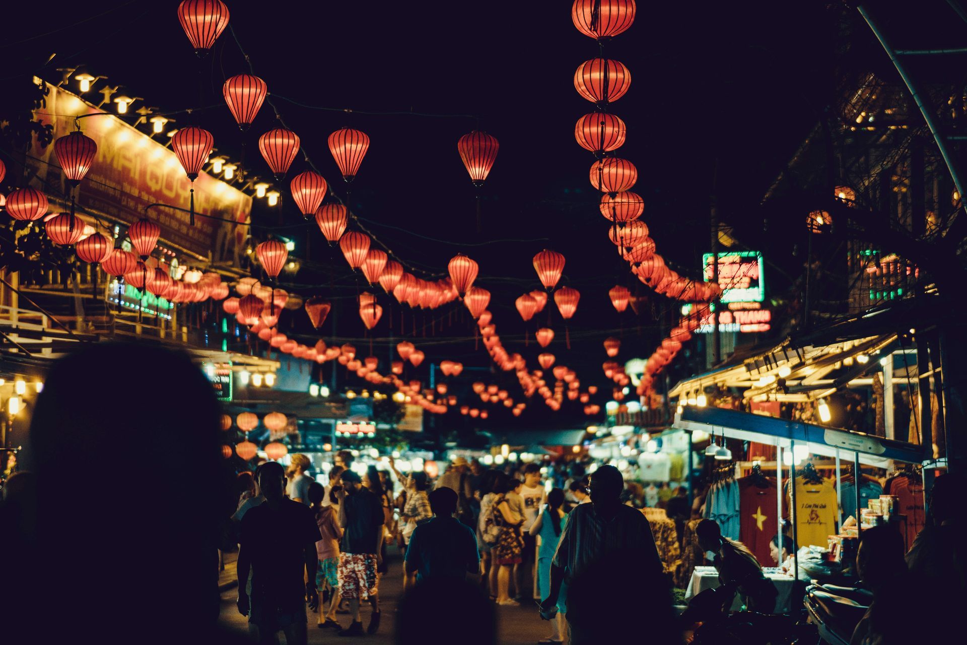 Night market with red lanterns, bustling crowds, illuminated stalls, and shops in Phú Quốc, Vietnam.