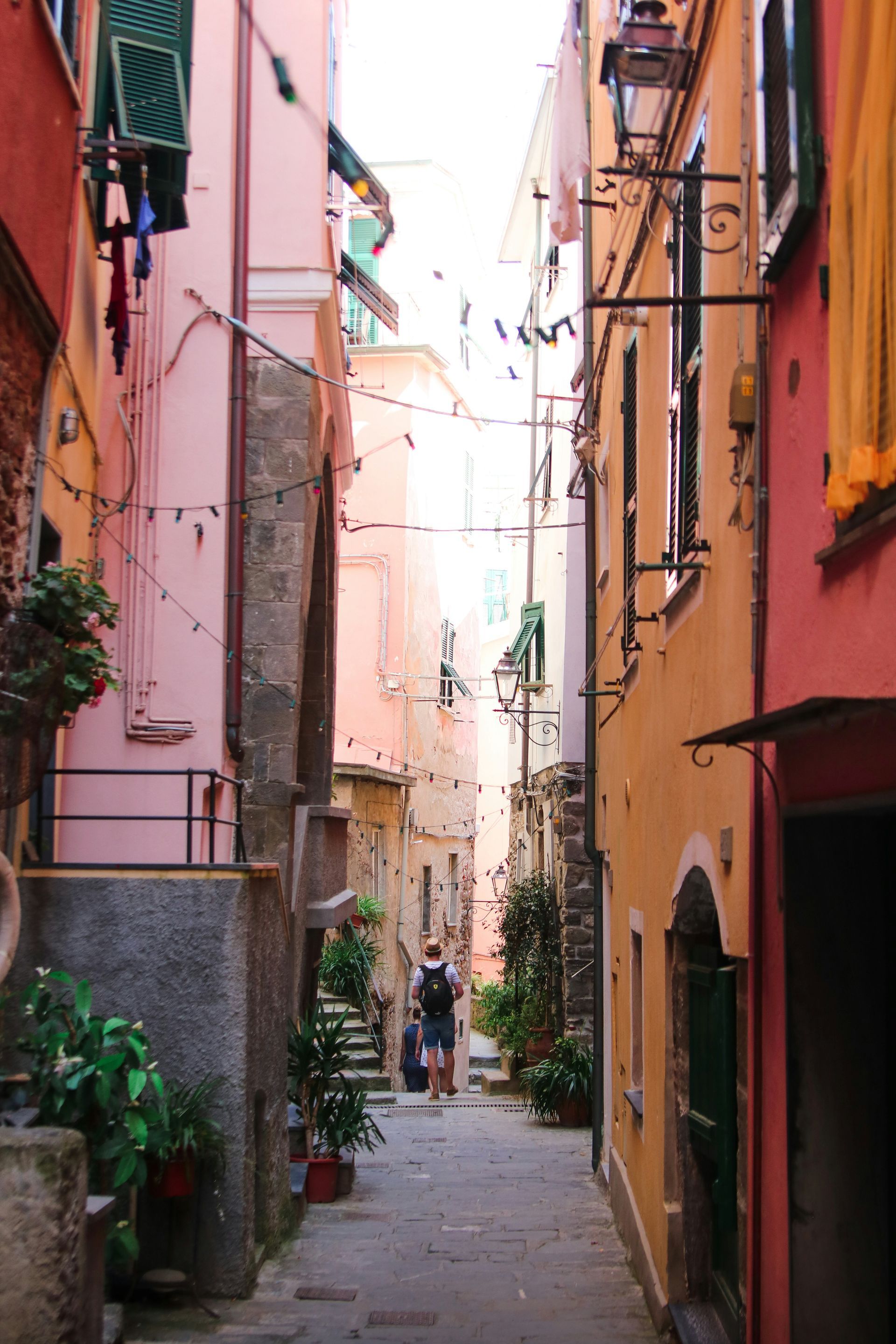 A man walking down a narrow alleyway between two buildings in Cinque Terre, Italy.