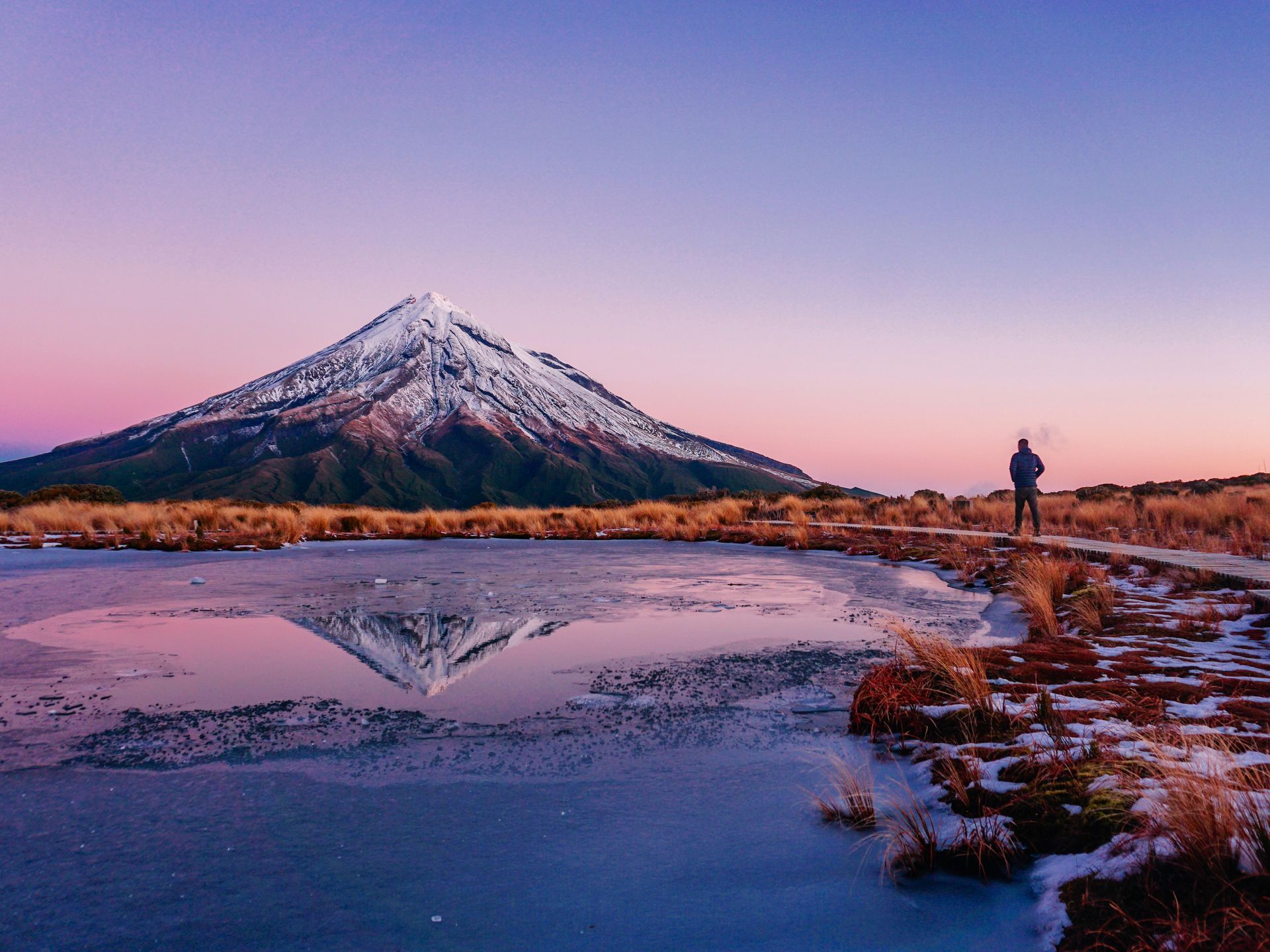 Mount Taranaki is reflected in Lake Mangamahoe at sunset in New Zealand. 