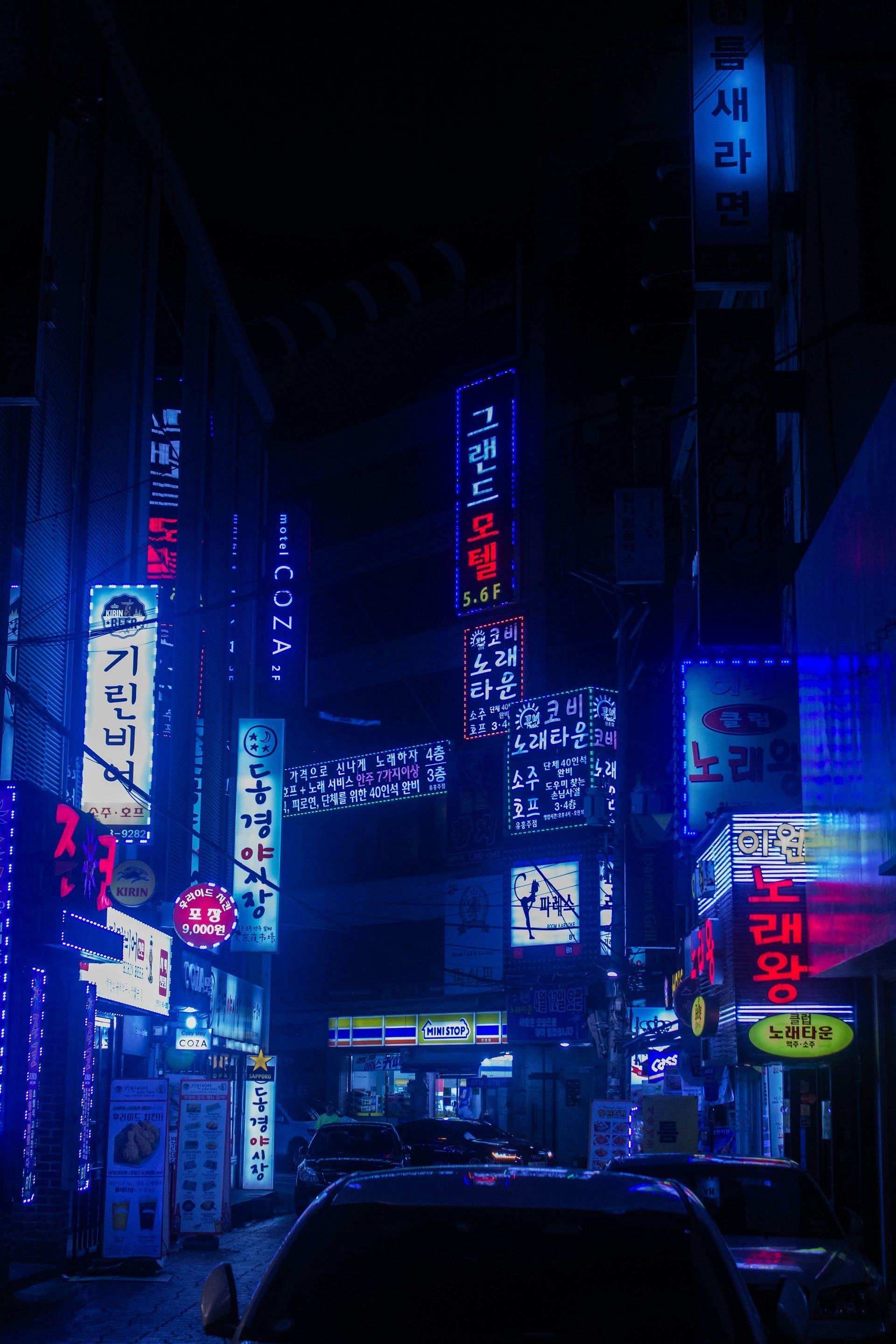 Dark alleyway illuminated by vibrant blue and red neon signs in Seoul, South Korea.