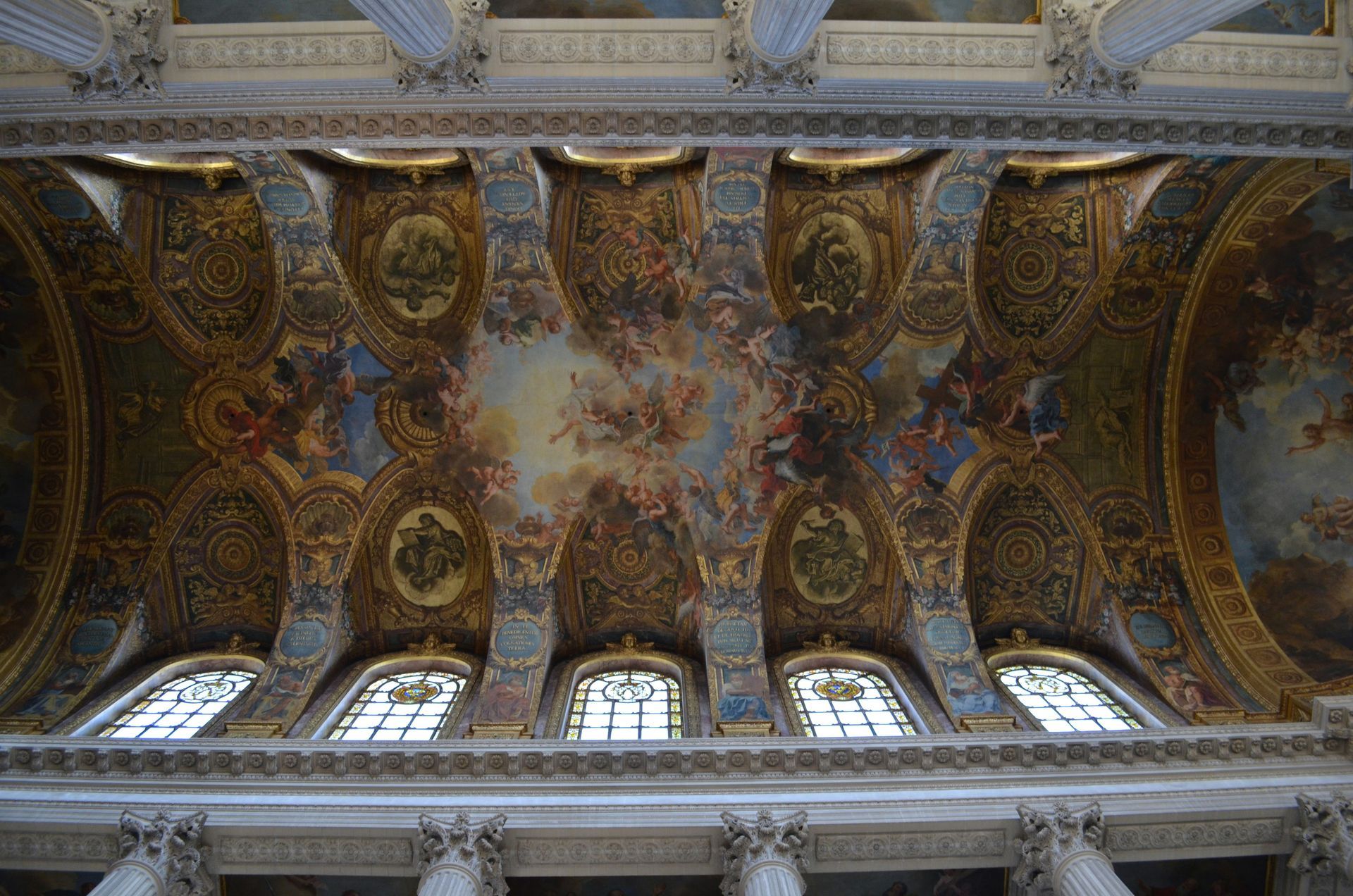 Looking up at the ceiling of a building with a painting on it at the Royal Chapel in Versailles, France.