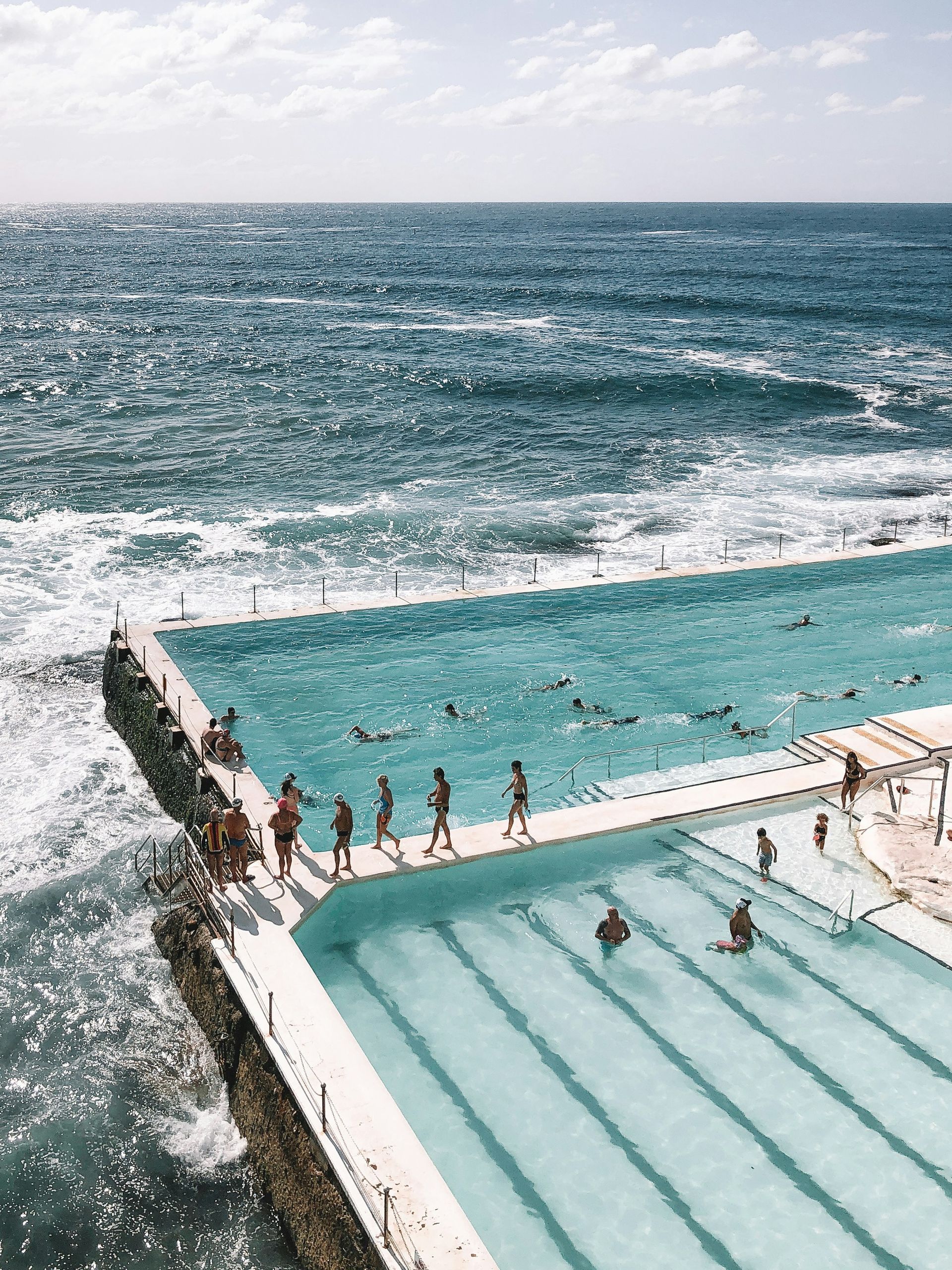 A group of people are swimming in a large swimming pool next to the ocean Sydney, Australia.