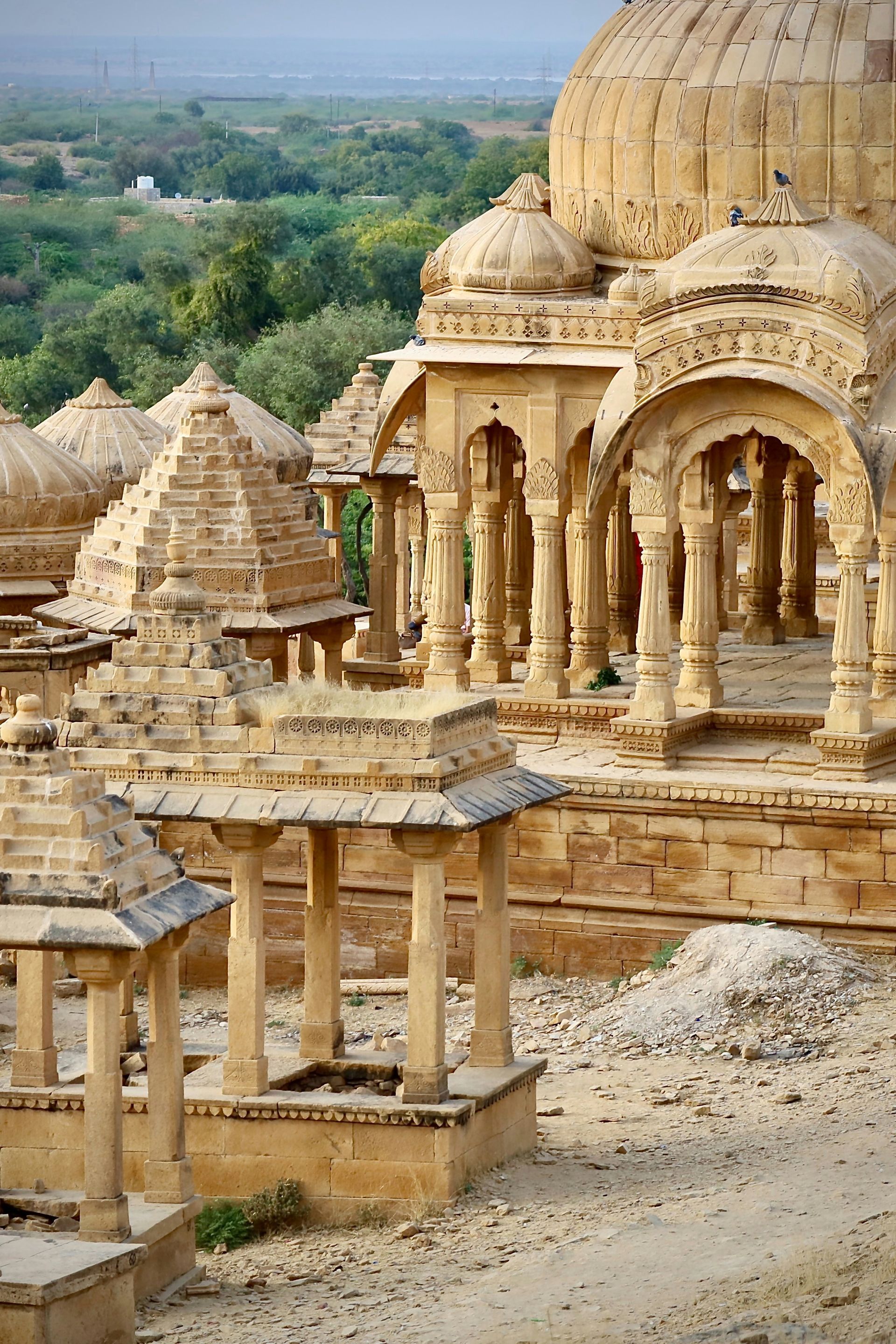 Yellow sandstone cenotaphs in a desert landscape in Jaisalmer, India.