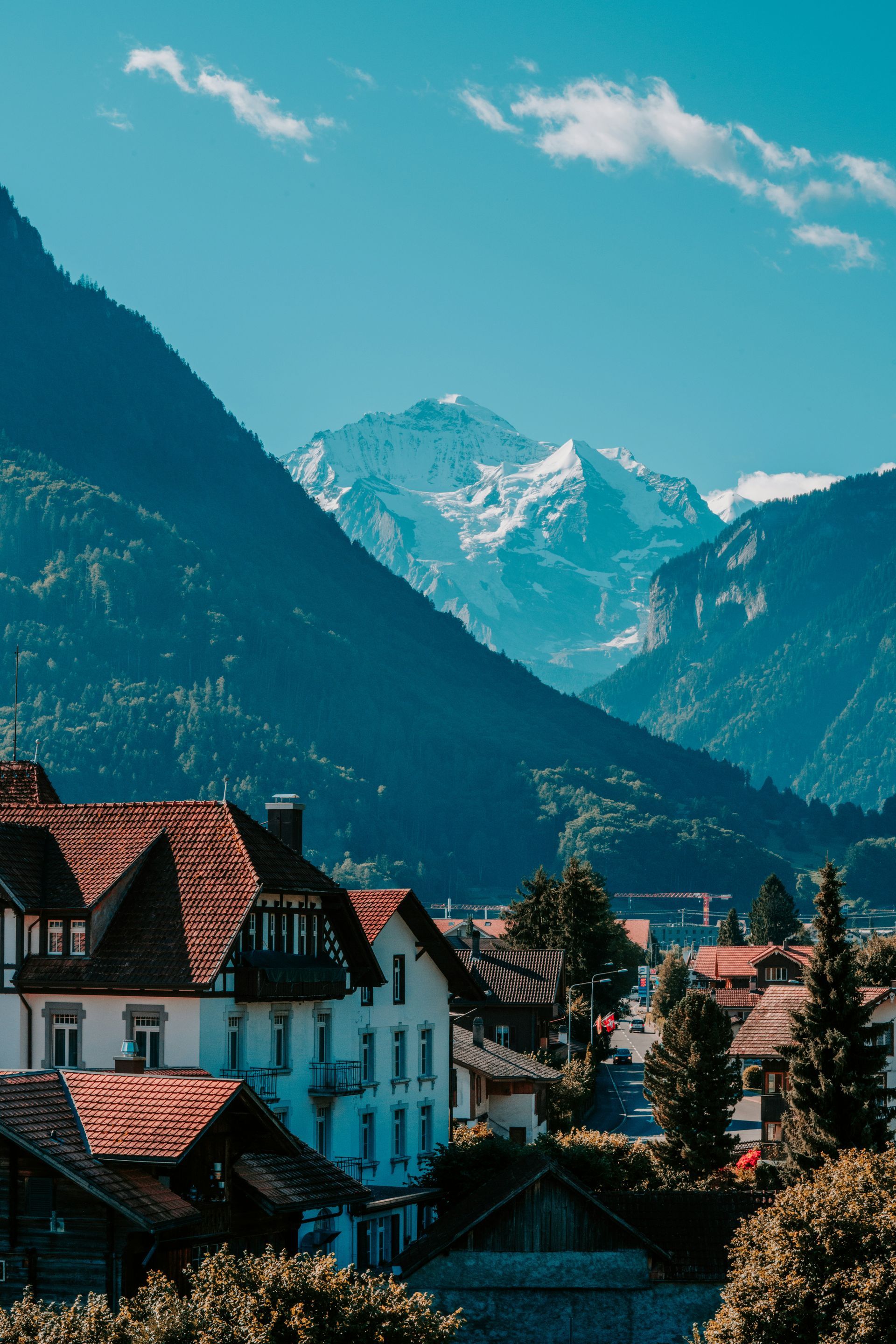 Houses with red roofs sit beneath a mountain range with snow-capped peak in Interlaken, Switzerland.