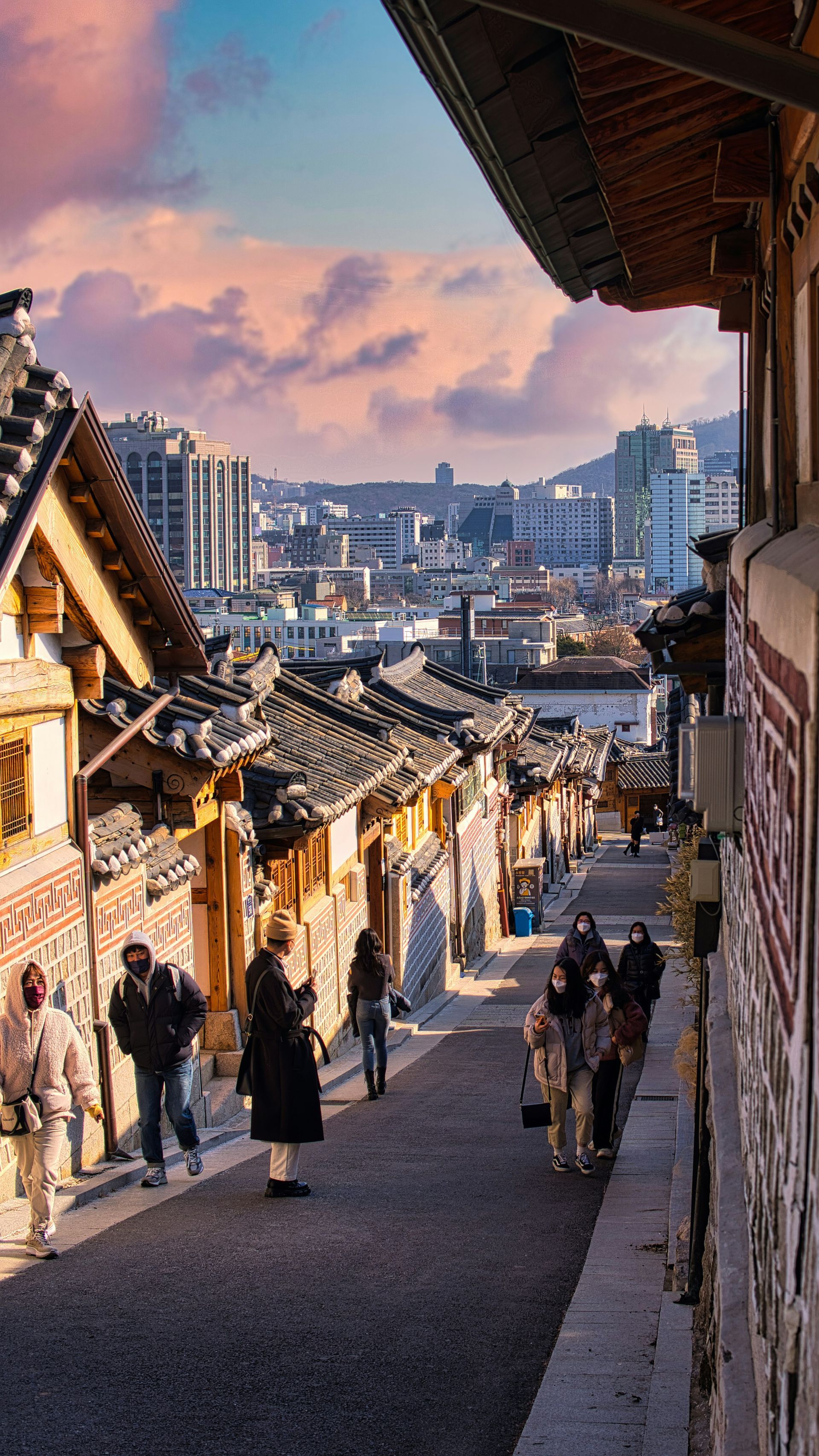 Cobblestone street in Bukchon Hanok Village; people walking past traditional buildings.