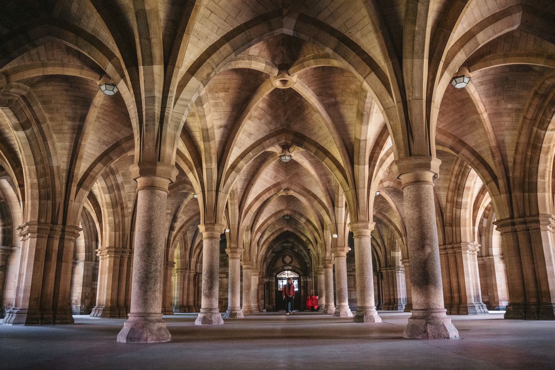 Stone arched hall with numerous pillars and a vaulted ceiling at the University of Glasgow in Scotland.