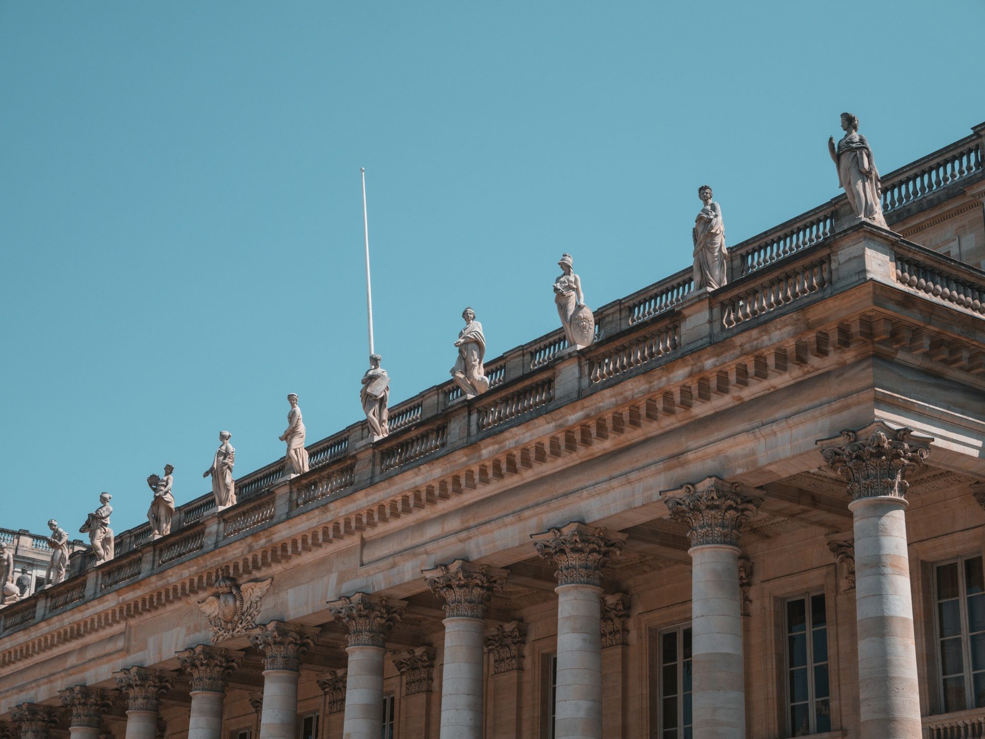The roof of a building with columns and statues on it in Bordeaux, France.