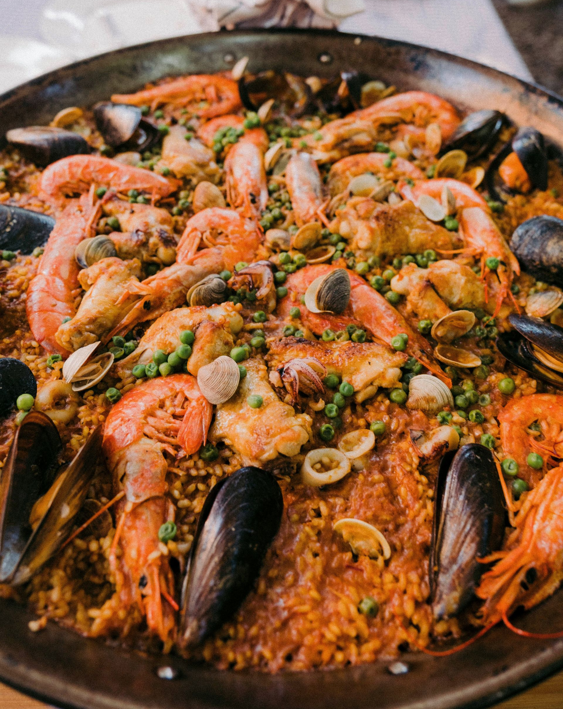 Paella with shrimp, mussels, peas, and other seafood in a large pan in Spain.