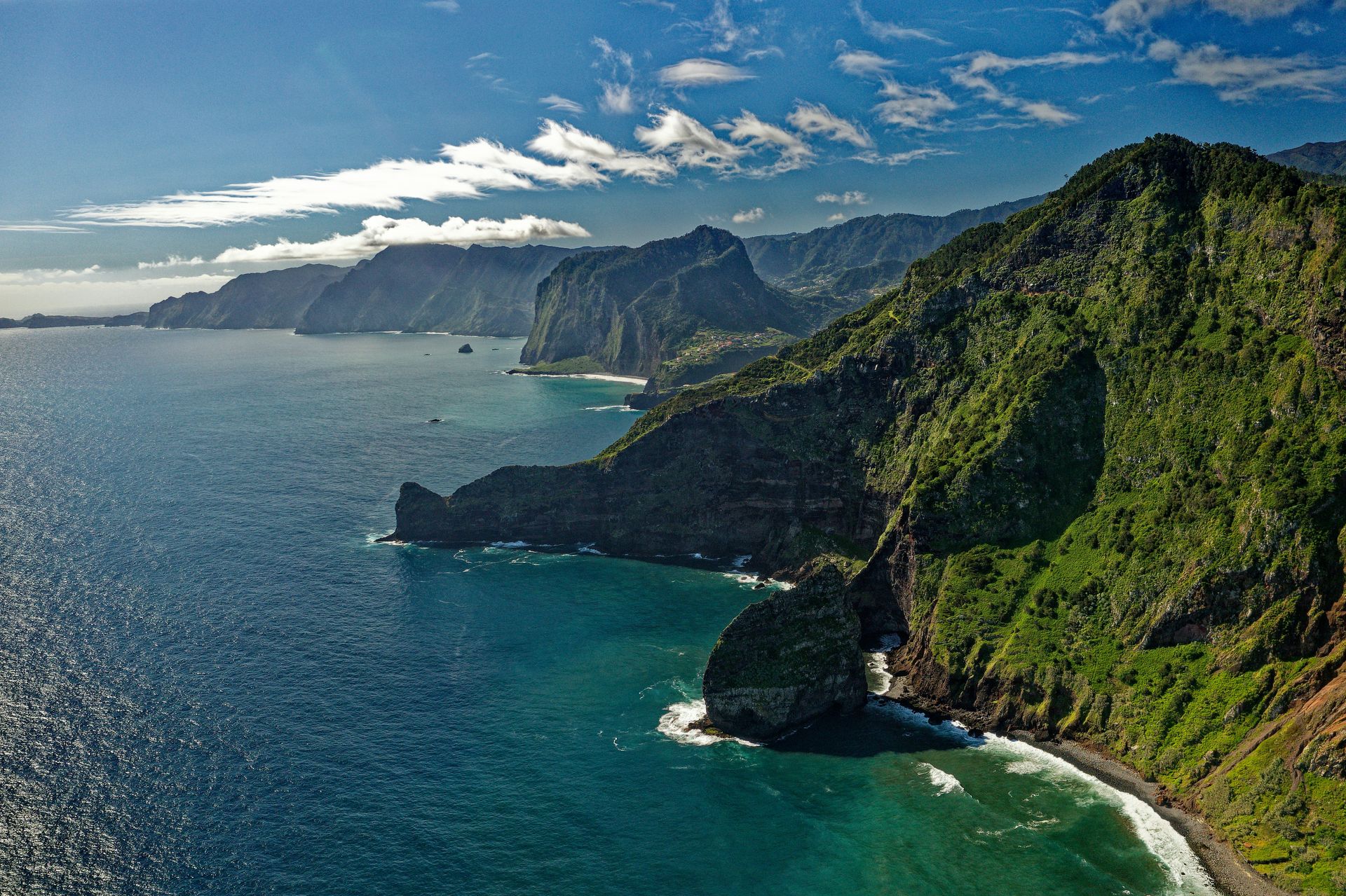 A cliff overlooking a body of water with mountains in the background in Madeira, Portugal.