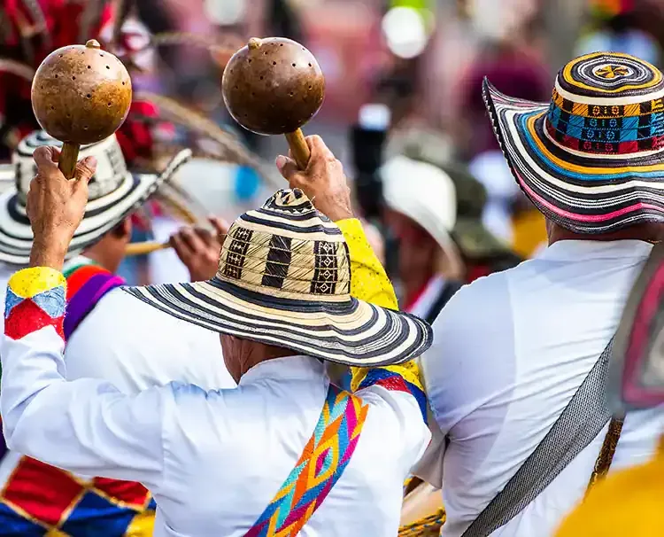 A group of people wearing colorful hats are playing maracas in a parade in Colombia.