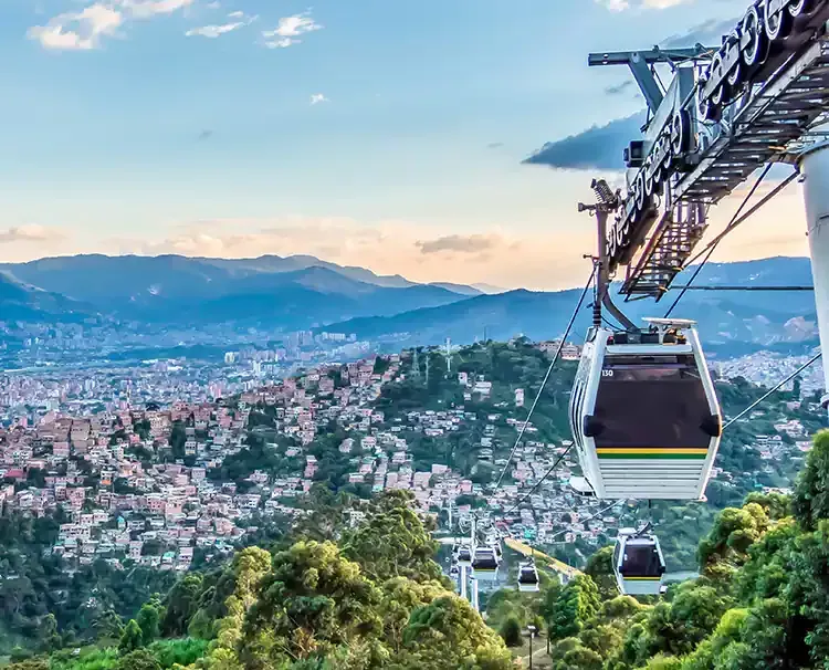 A cable car is going up a hill overlooking a Medellín, Colombia.