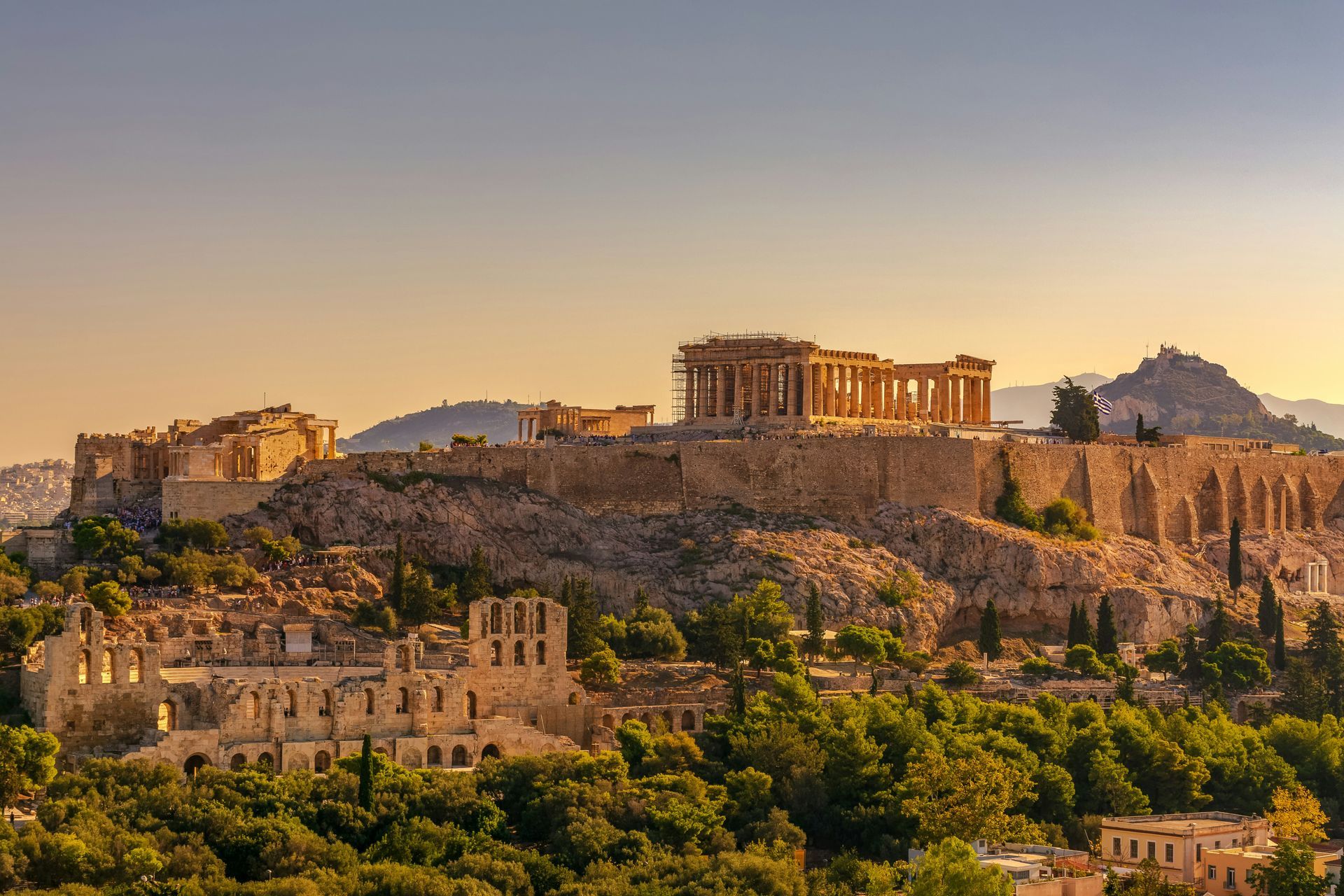 The Acropolis in Athens, Greece, is surrounded by trees and mountains.