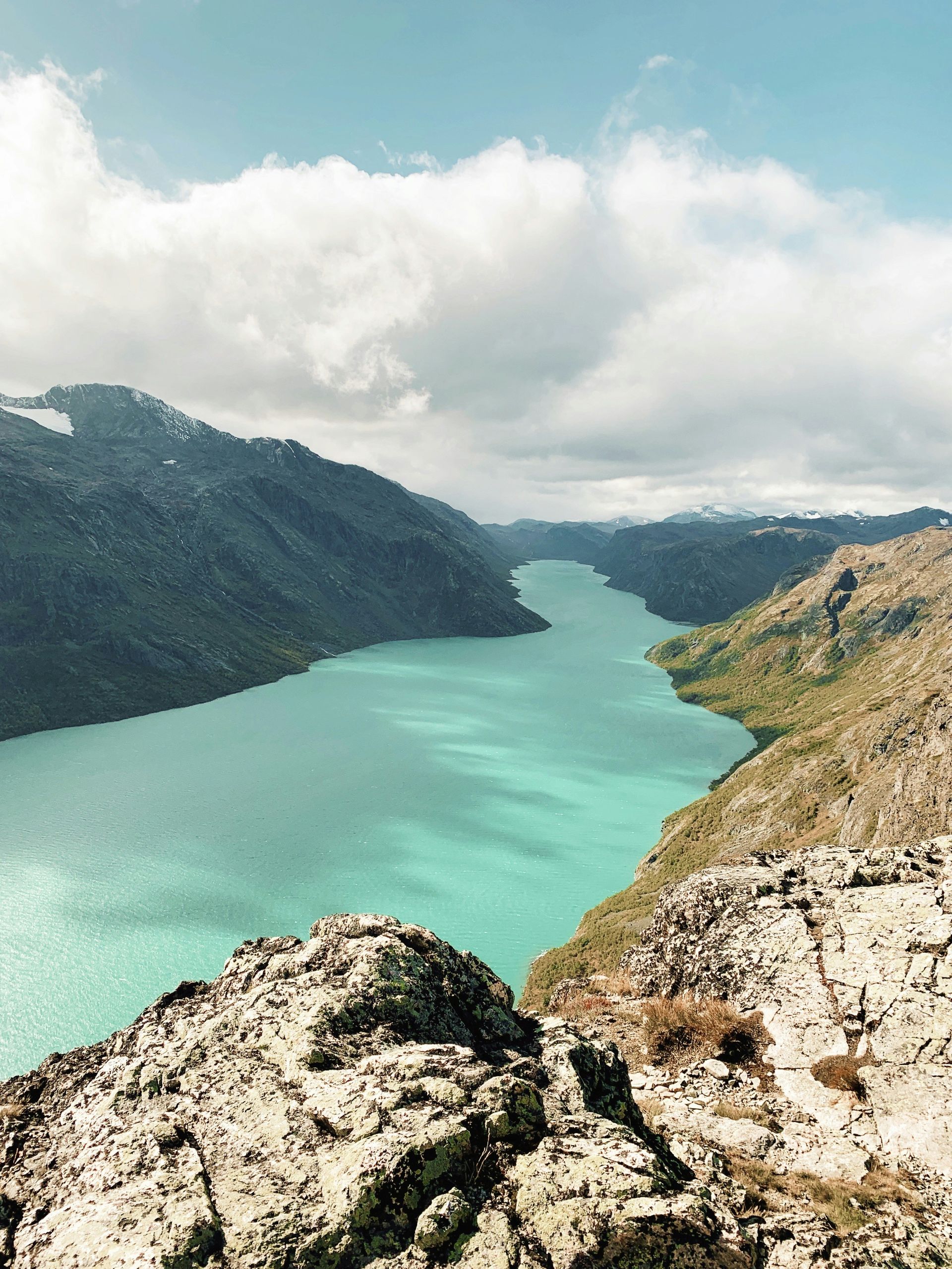 Turquoise lake winding through mountainous landscape in Jotunheimen National Park, Norway.