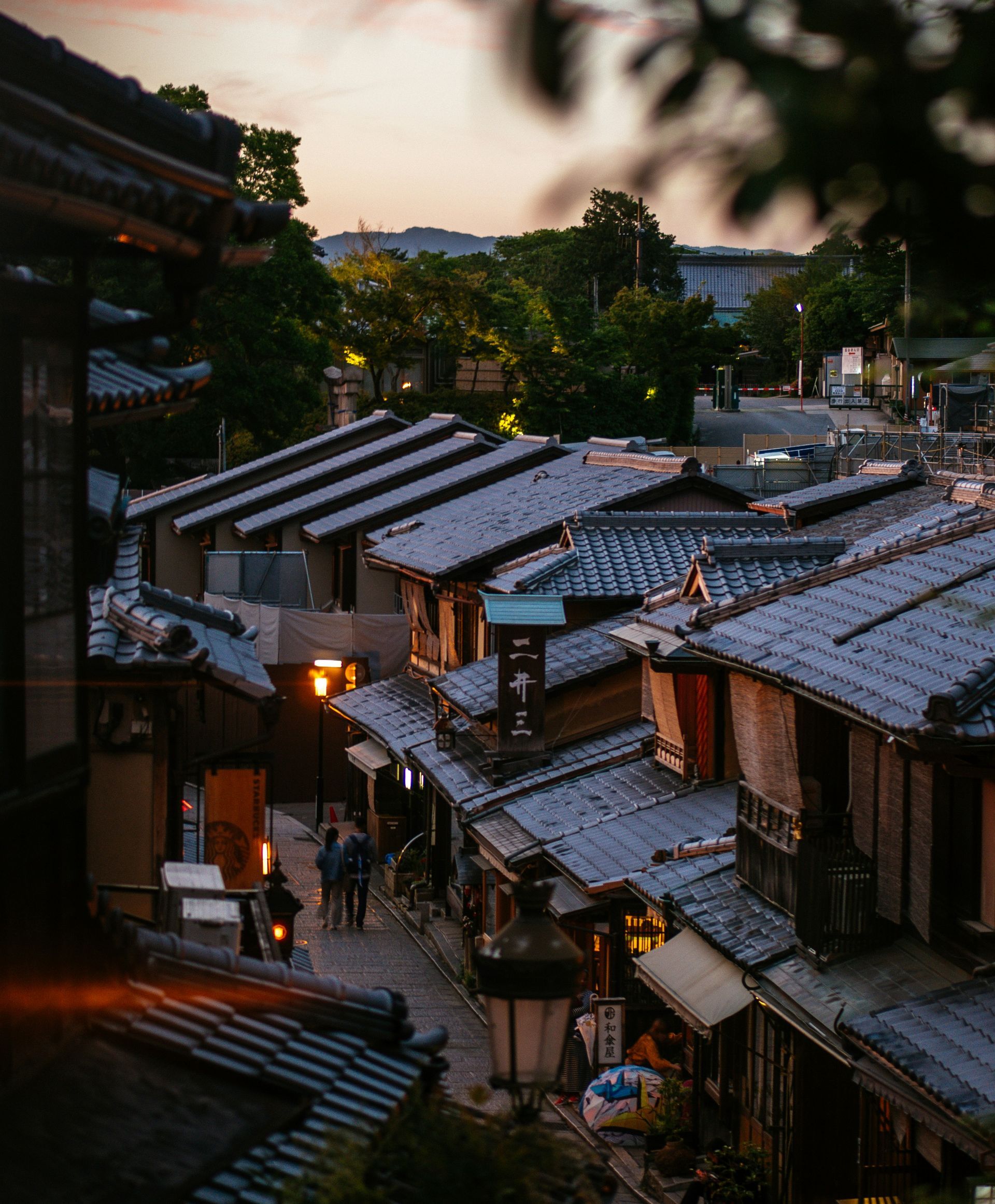 Narrow street lined with traditional Japanese buildings at dusk in Kyoto, Japan.