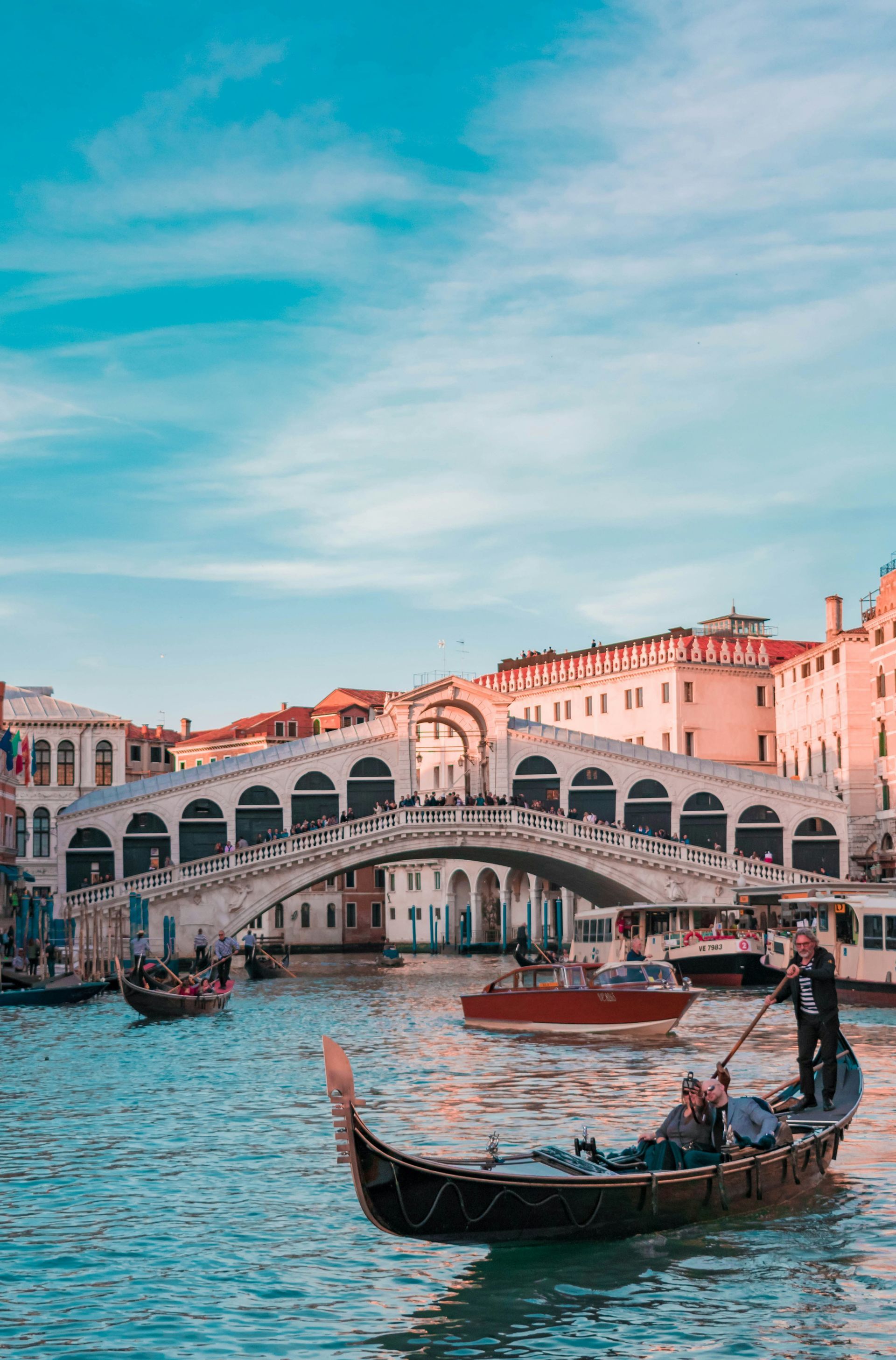 A man is riding a gondola down a river in Venice.