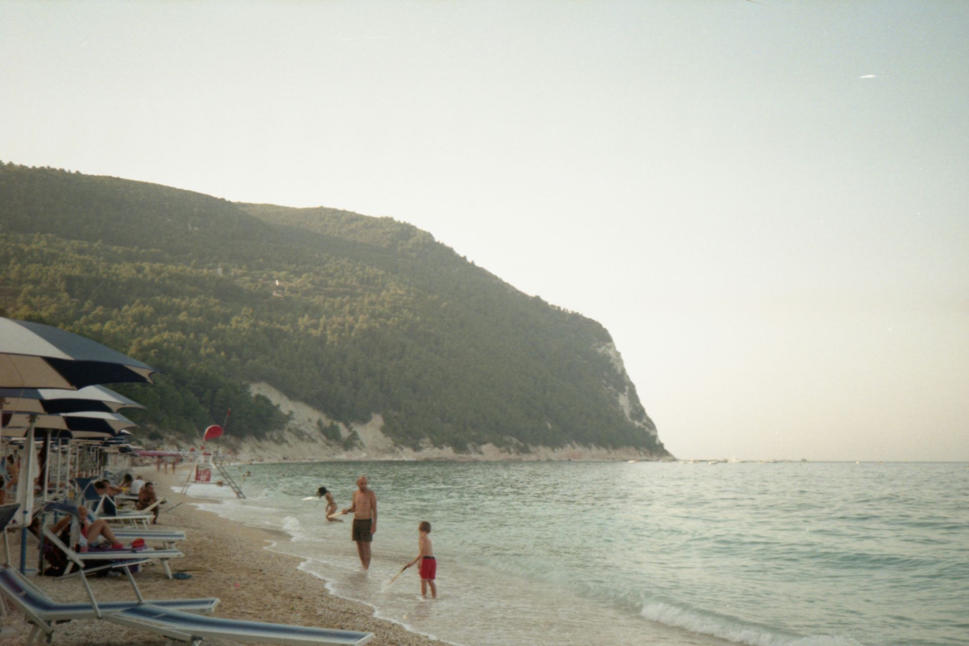 A group of people are playing in the water on a beach in Sirolo, Italy