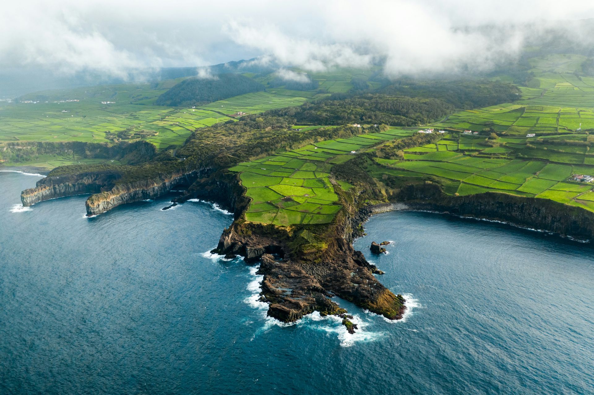 Coastal landscape with green fields, cliffs, and the ocean on the island of Azores, Portugal.