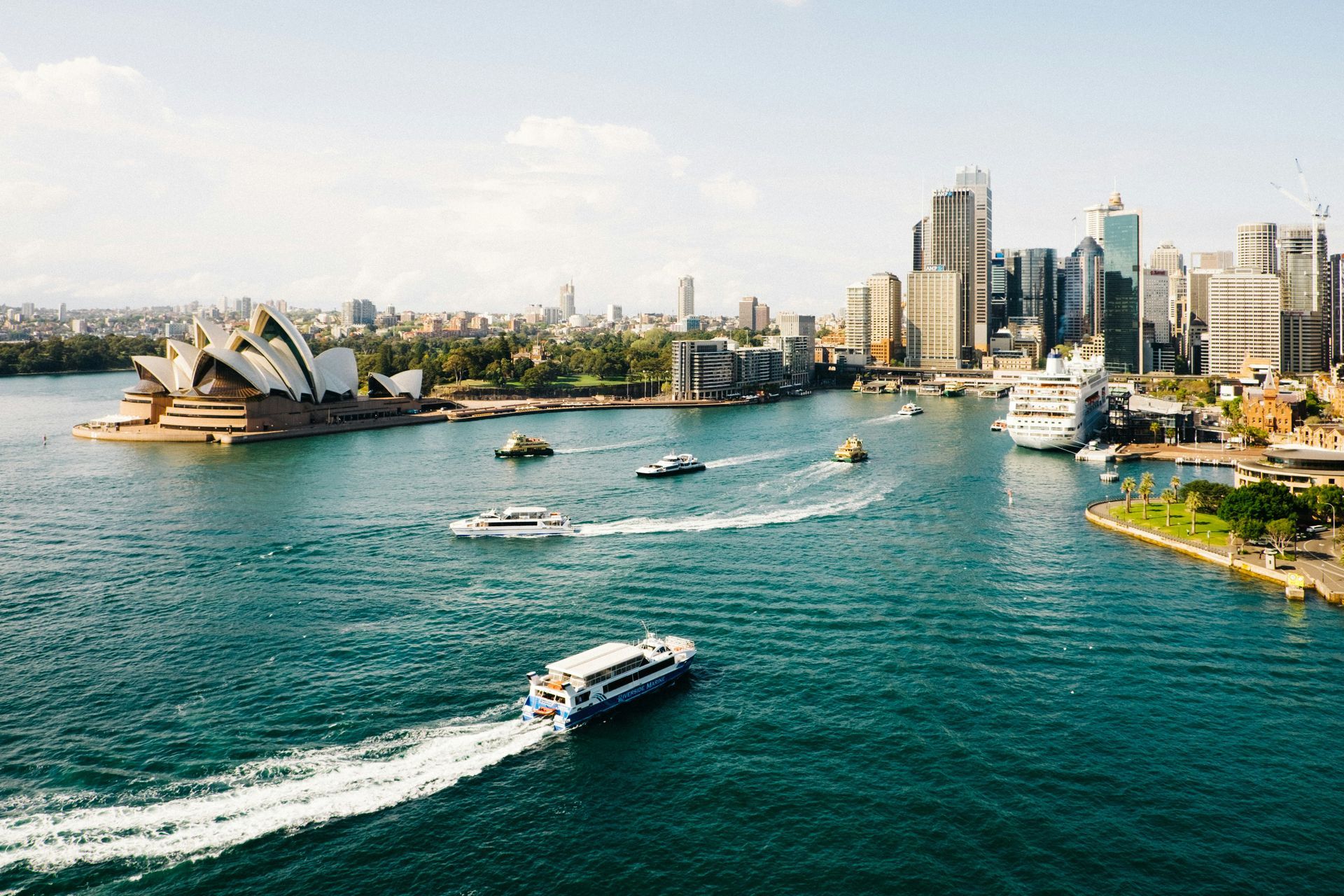 A group of boats are floating on top of a body of water in Sydney, Australia.