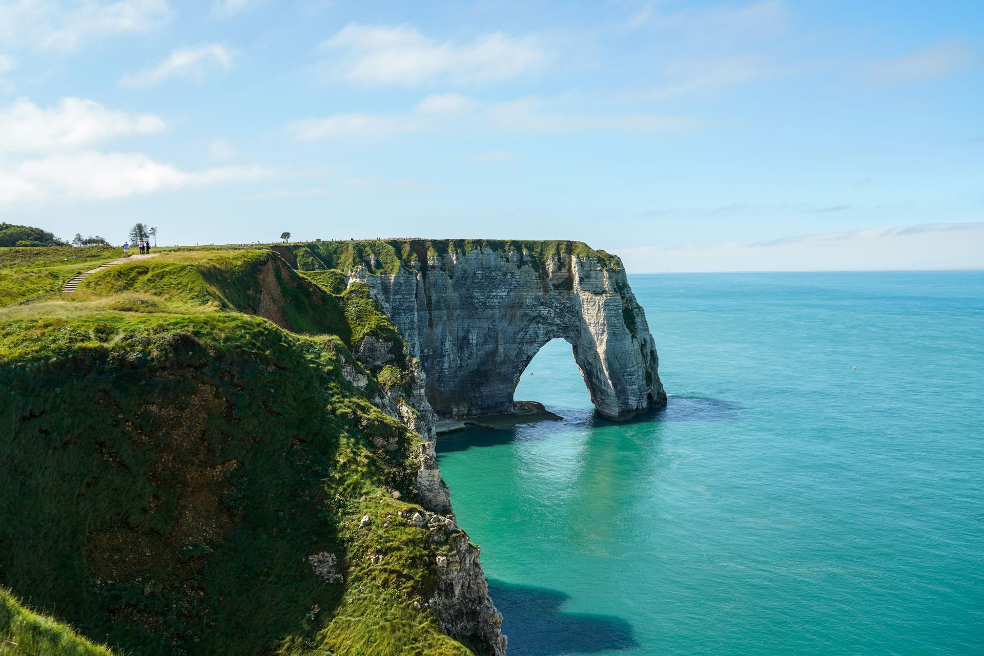 A cliff overlooking the ocean with a large arch in the middle of it at Étretat beach in Normandy, France.
