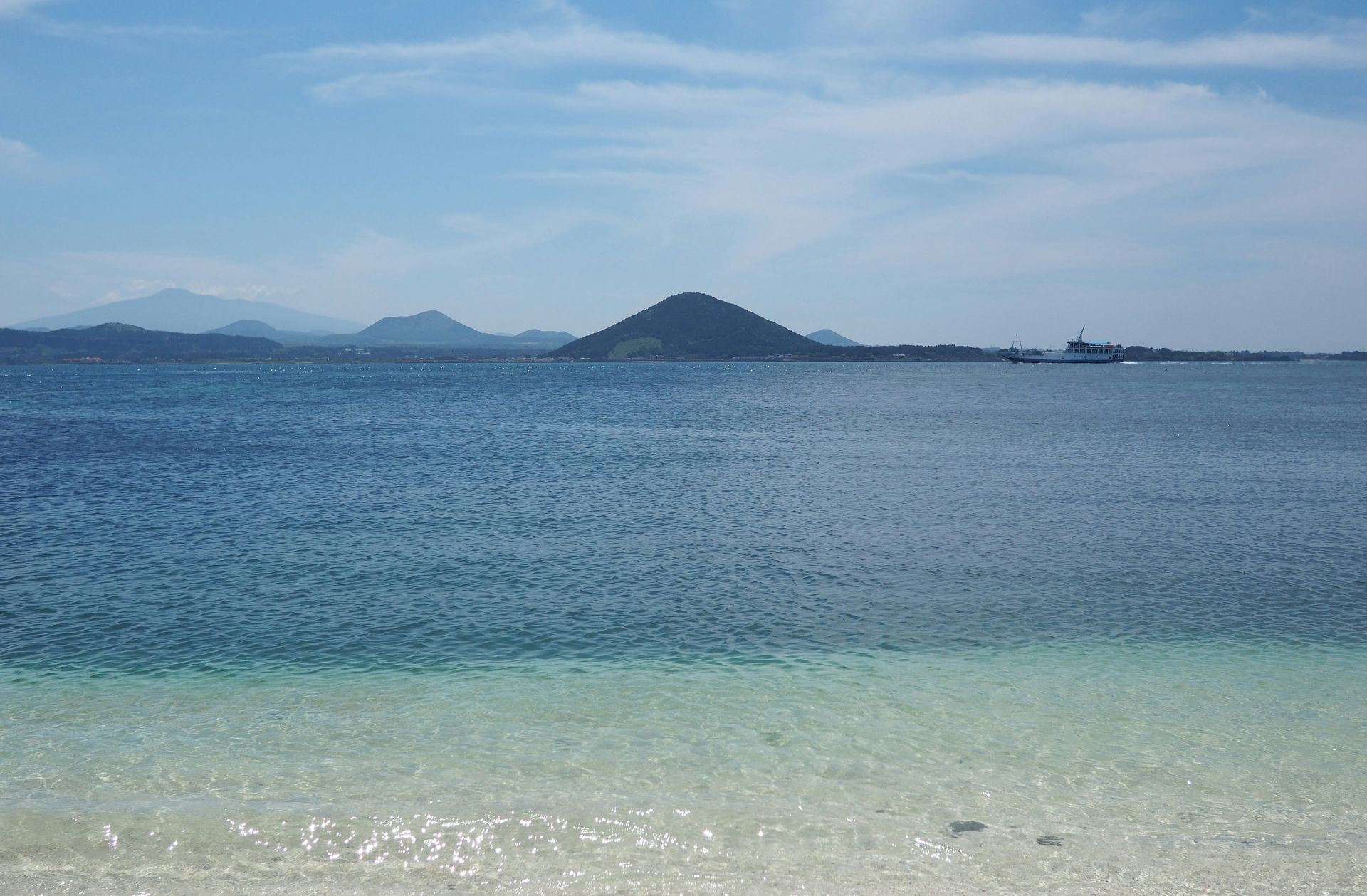 Ocean view with a small island in the distance and a ferry on Jeju Island, South Korea.