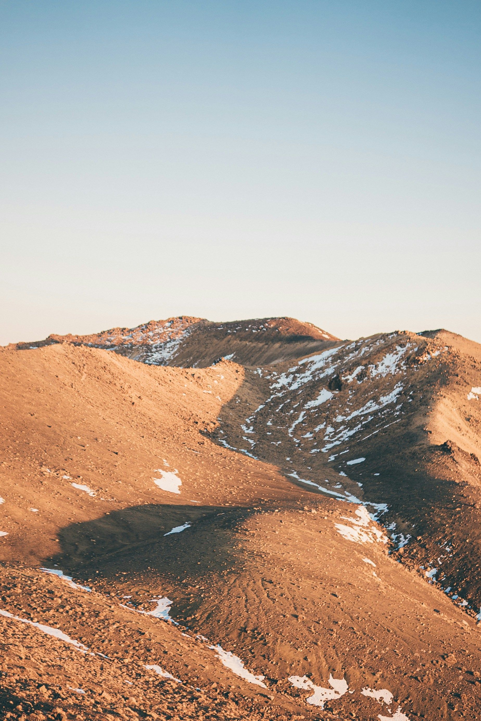 A person is standing on top of a snowy mountain in Tongariro National Park, New Zealand.