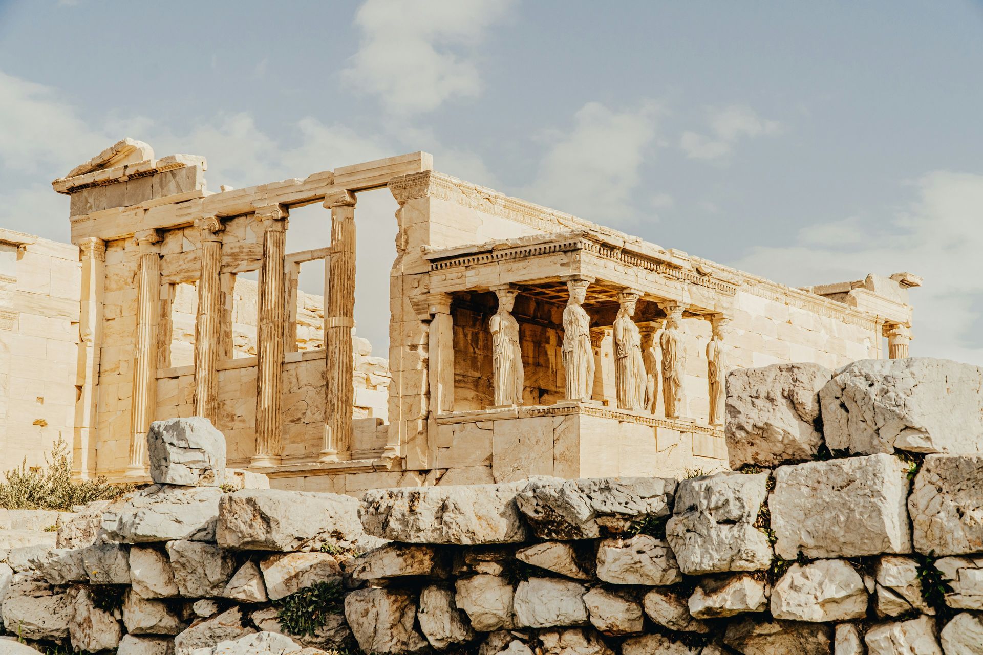 A very old building with a stone wall in front of it in Greece.