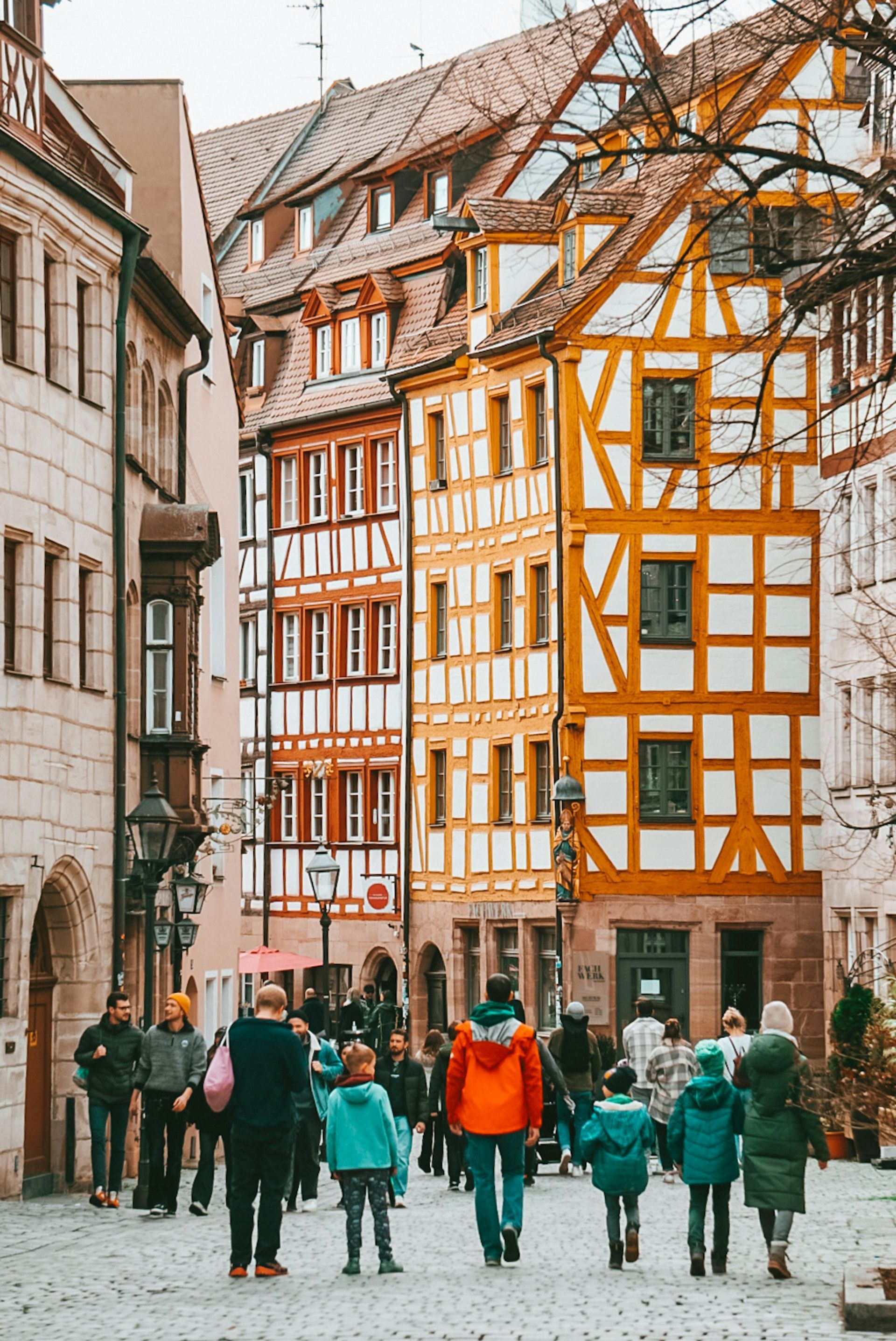 Cobblestone street with people walking past colorful half-timbered buildings in Nuremberg, Germany.