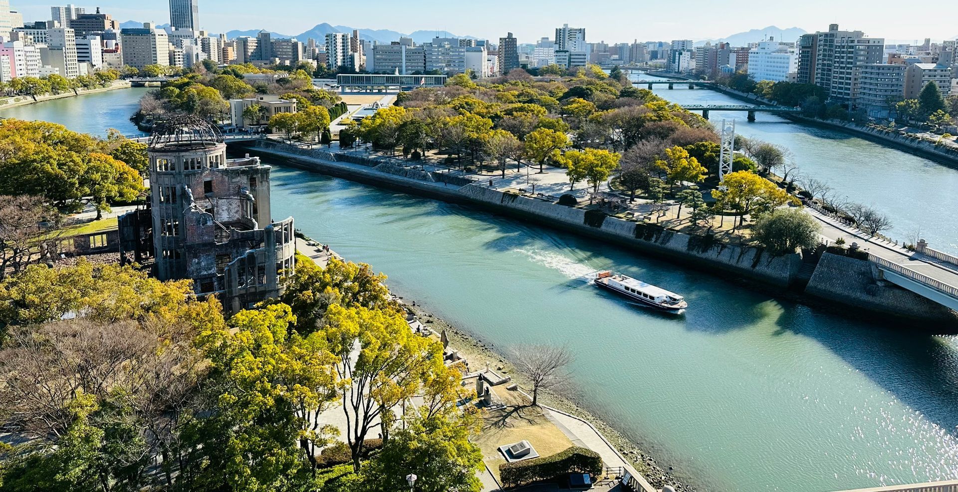 Hiroshima Peace Memorial Park, river, boat, and city skyline.