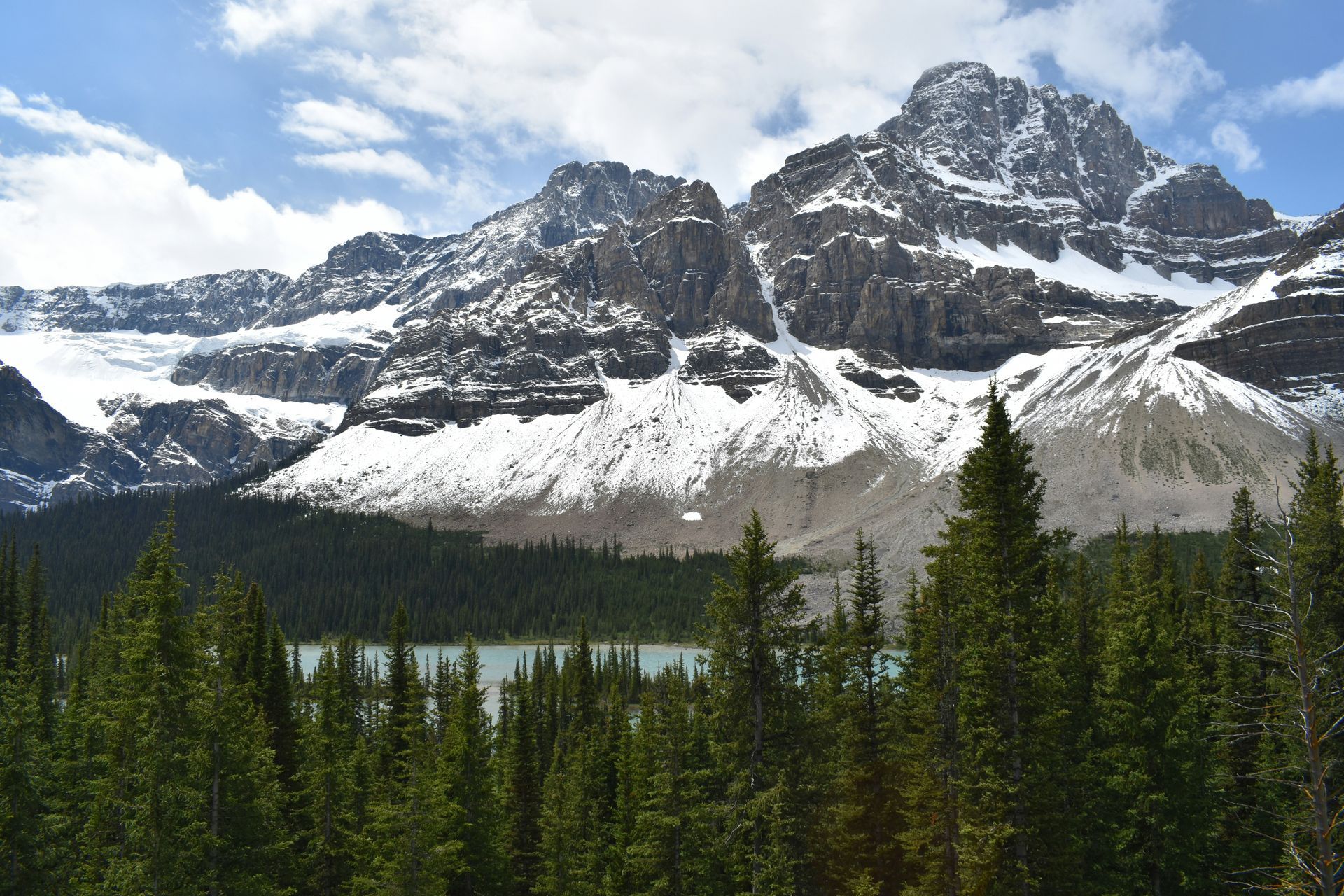 Trees and a lake in Jasper, Canada surround a mountain covered in snow.
