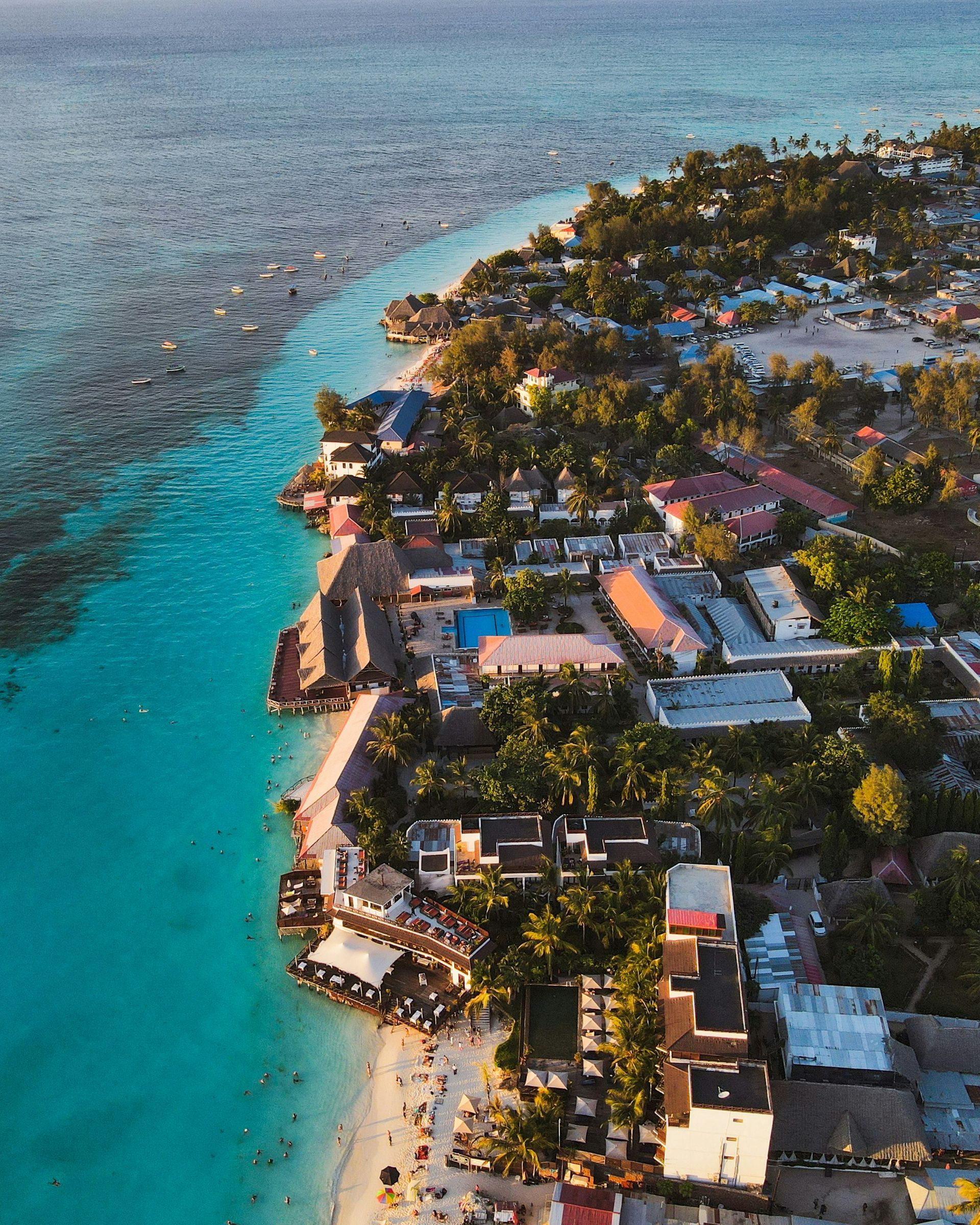 An aerial view of a beach with buildings and trees in Zanzibar, Tanzania.