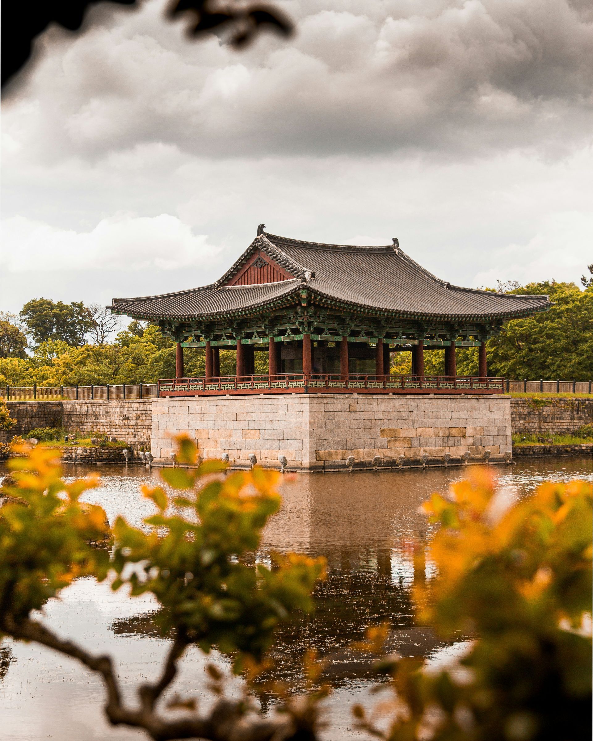 Traditional Korean pavilion reflected in water, surrounded by foliage in Gyeongju, South Korea.
