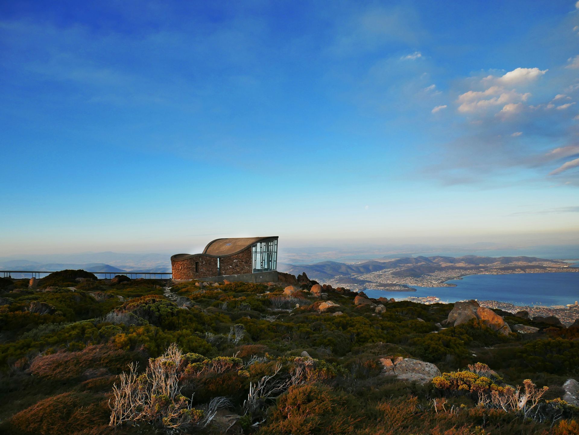 A small house is sitting on top of a hill overlooking a body of water in Tasmania, Australia.