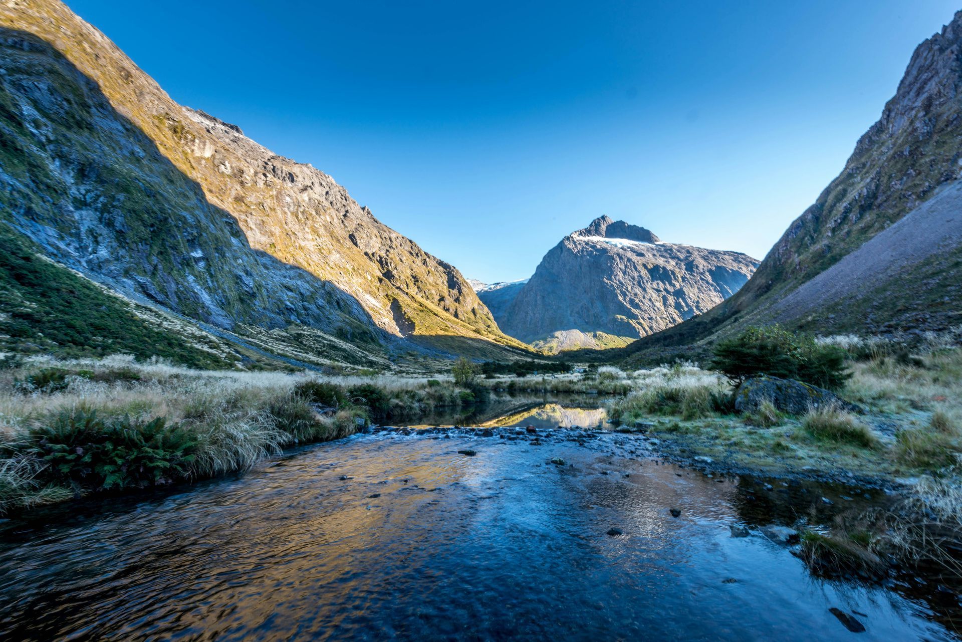 The Milford Sound runs through a valley between two mountains in Fiordland National Park, New Zealand.