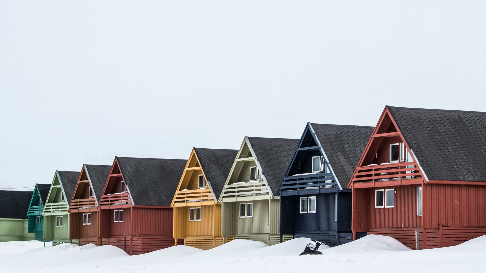 Row of colorful wooden houses with snow in front in Svalbard, Norway.
