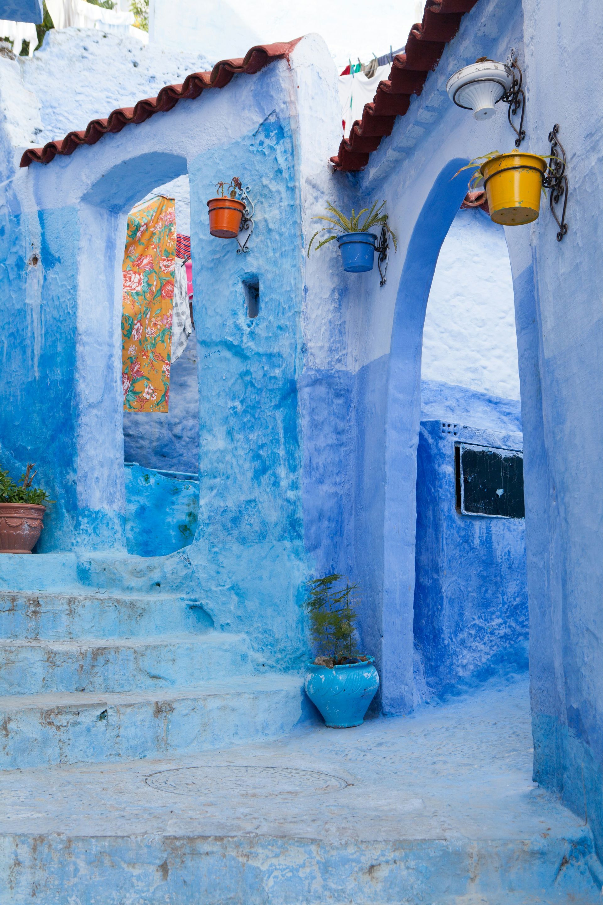 A blue building with stairs and potted plants on the side in Chefchaouen, Morocco.