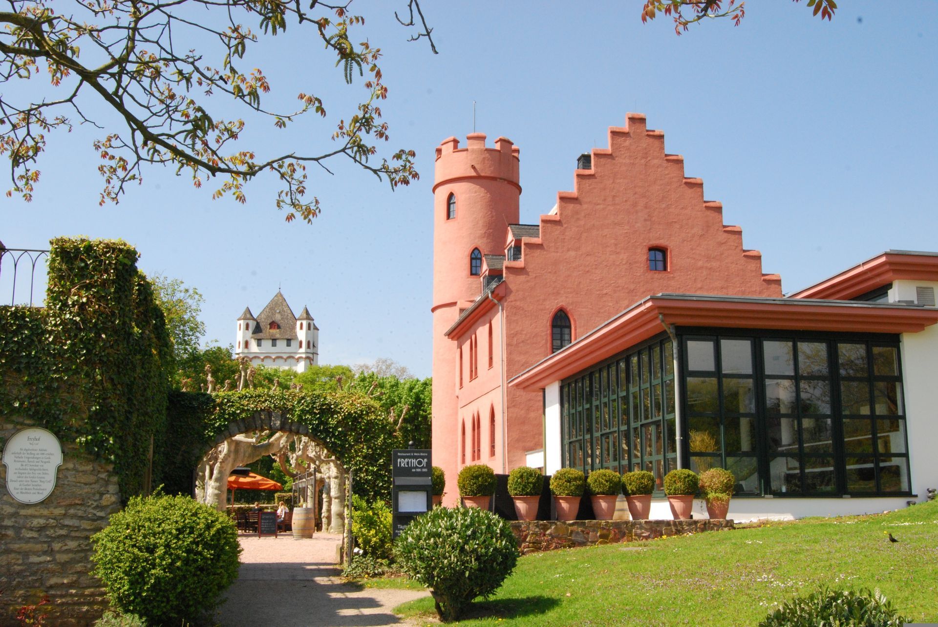 A large red brick building with a castle in the background in Eltville, Germany.