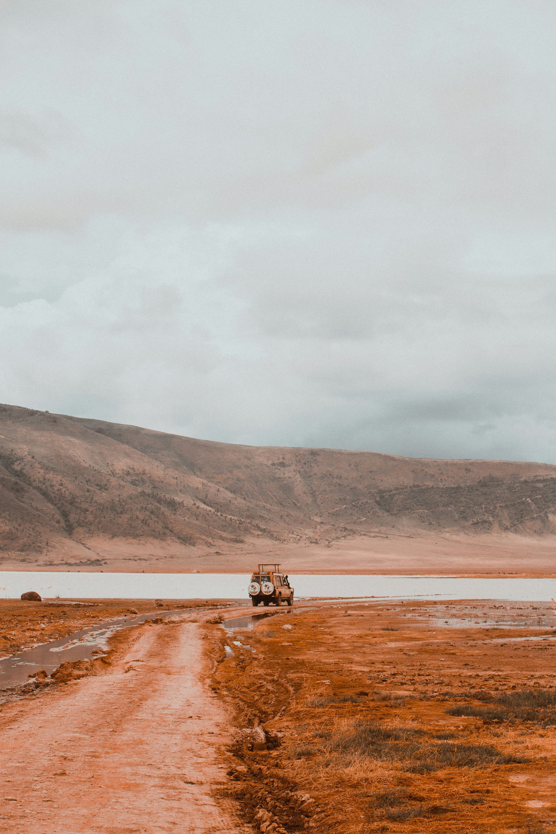 A dirt road leading to a lake with mountains in the background in the Ngorongoro Crater, Tanzania.