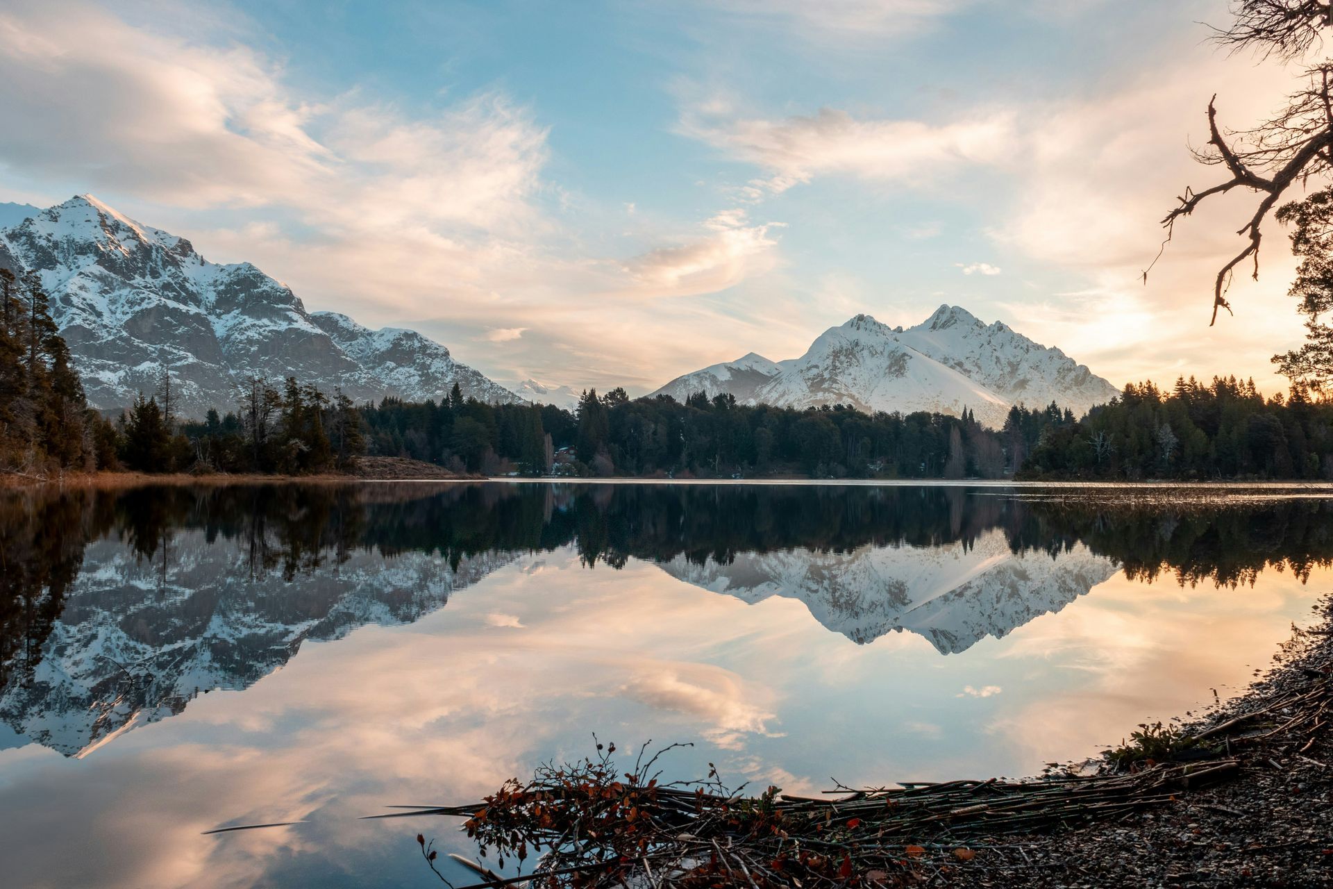Snowy mountains reflected in calm lake at sunset in San Carlos de Bariloche, Argentina.
