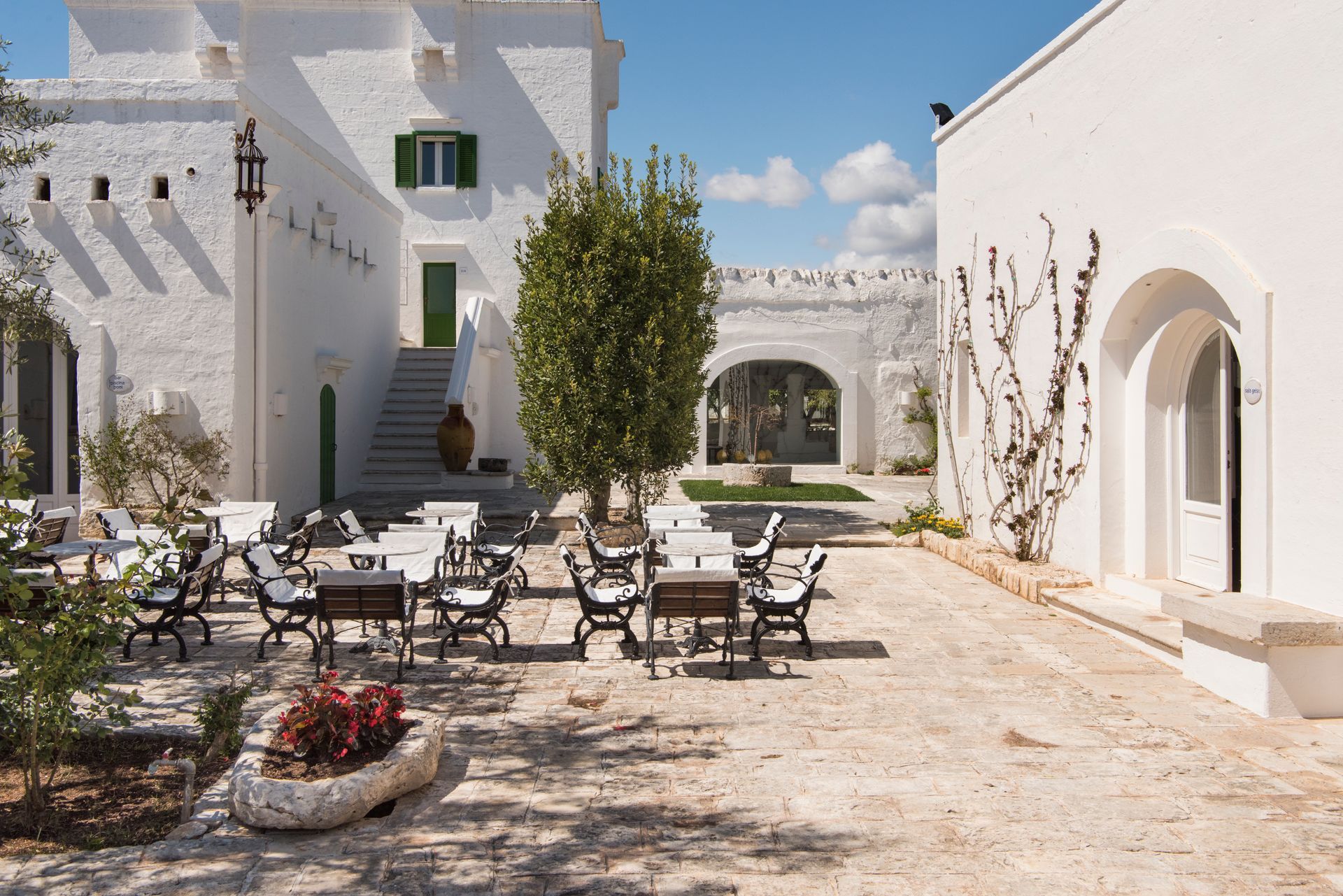 A white building with tables and chairs in front of it at Il Melograno Hotel in Puglia, Italy.