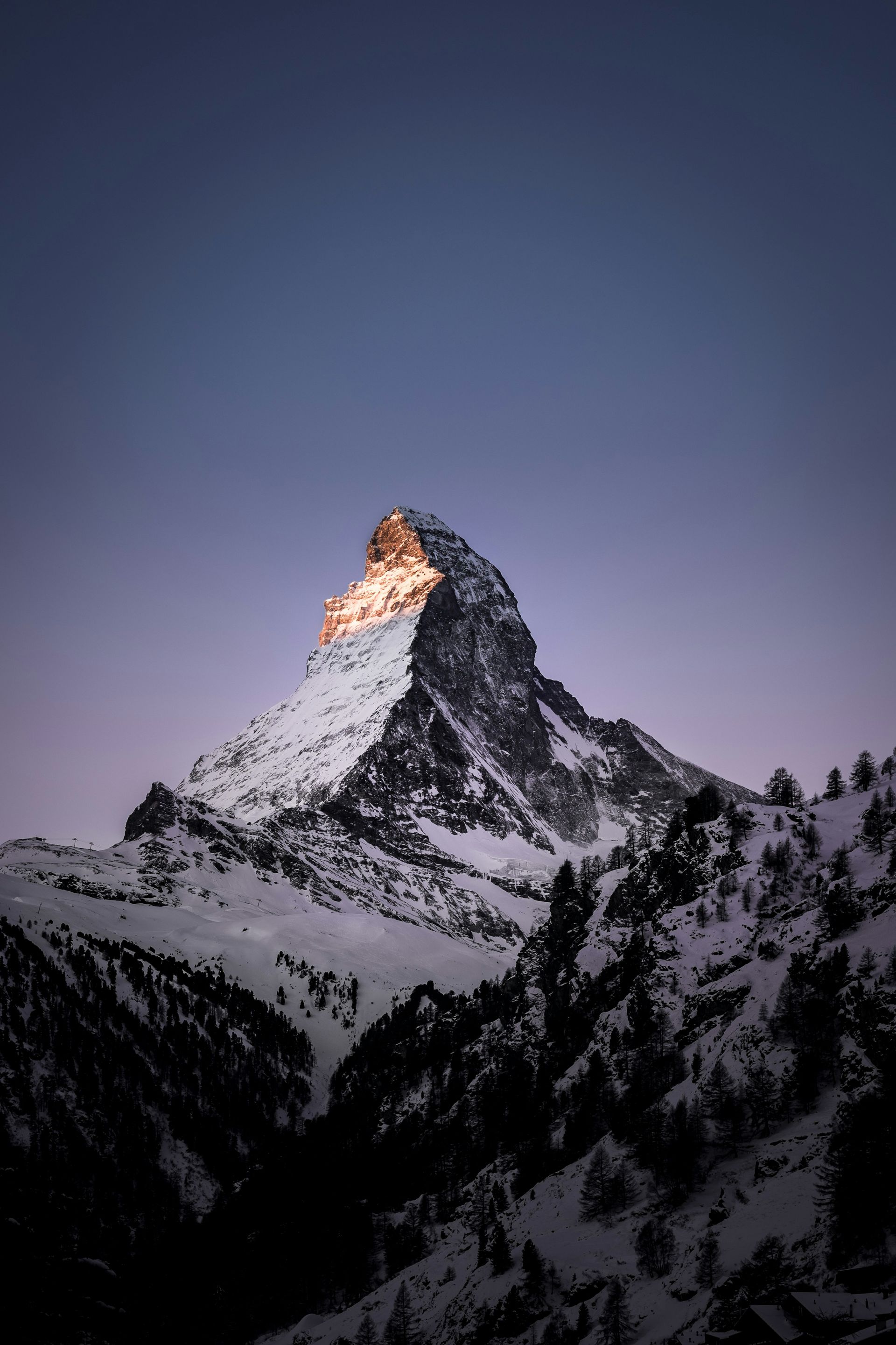 Snow-covered Matterhorn peak at sunrise with a golden glow.