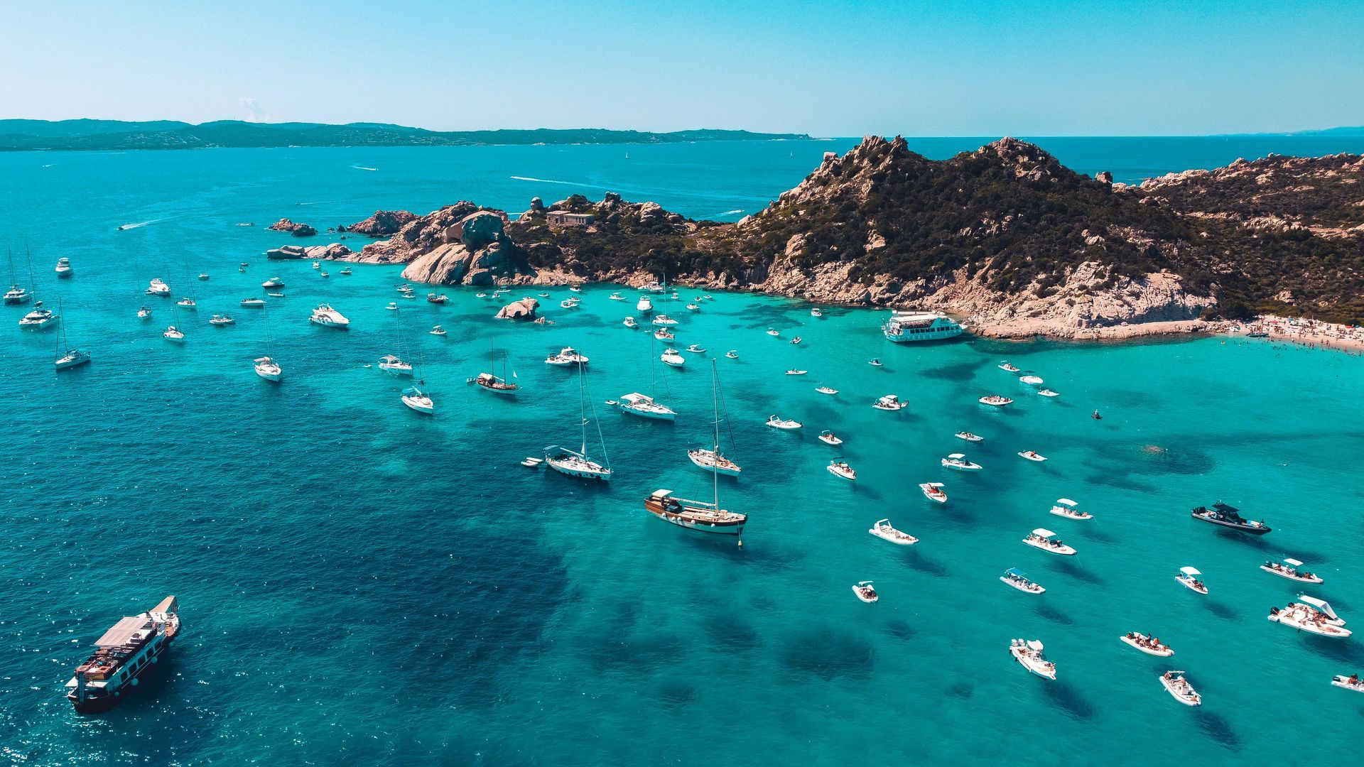 An aerial view of a large body of water filled with boats in Sardinia, Italy.