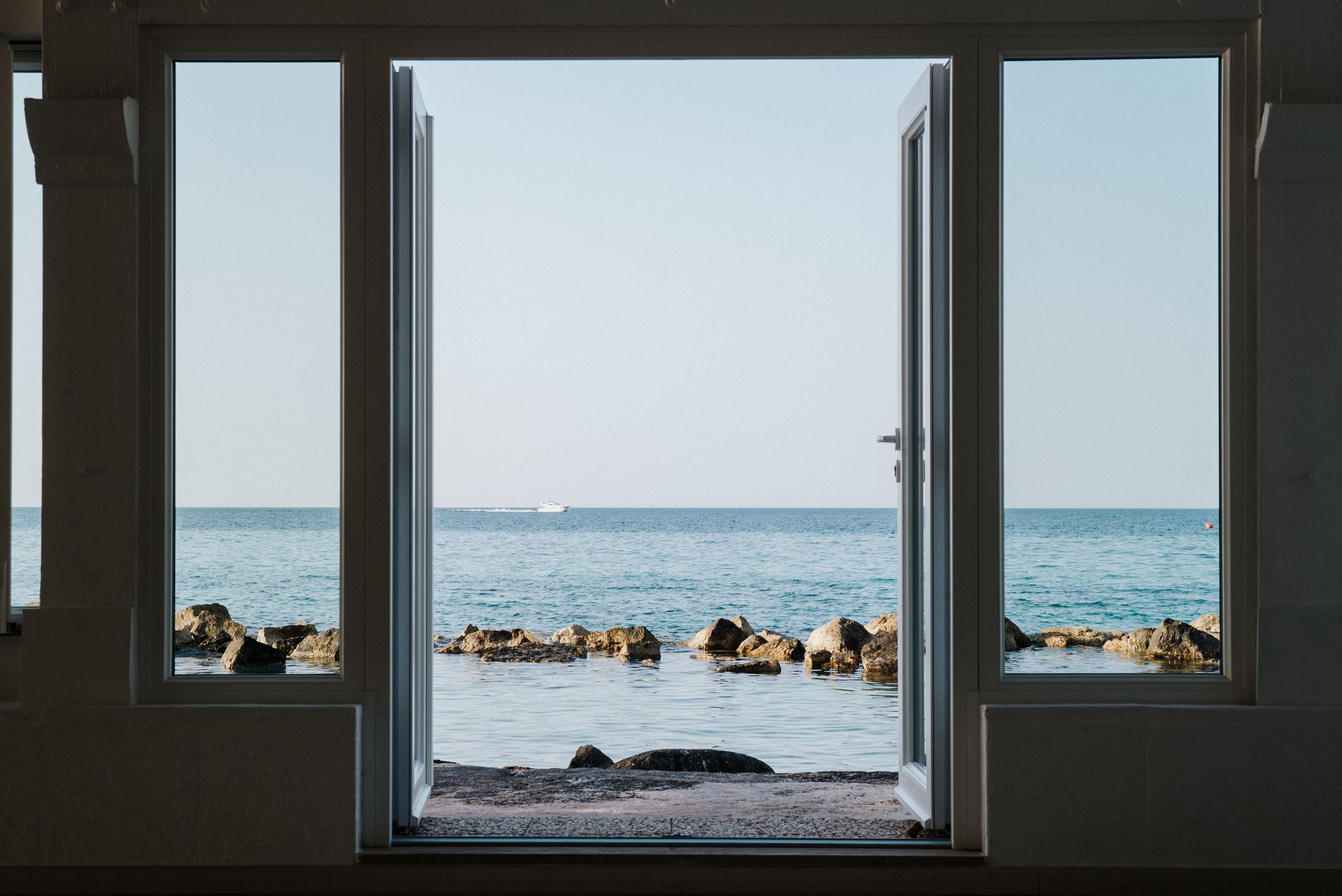 A view of the ocean through an open window at La Peschiera Hotel in Puglia, Italy.