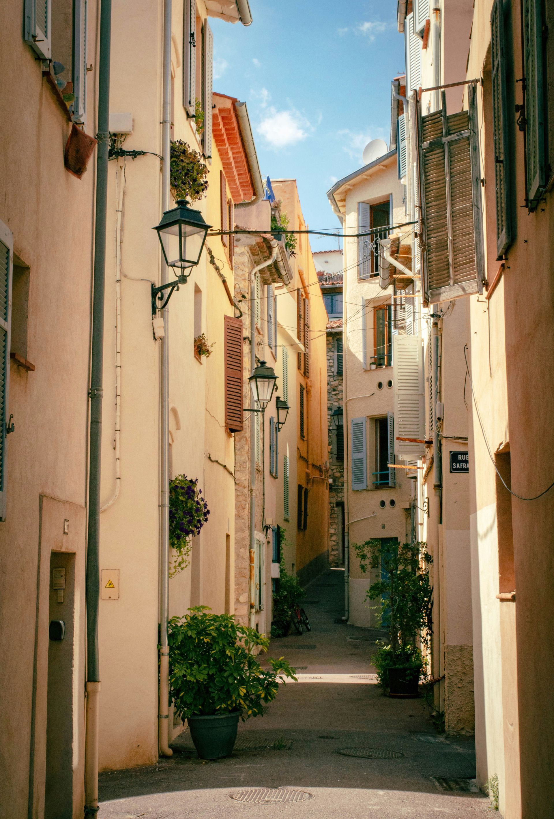 A narrow alleyway between two buildings with potted plants on the sideon the French Riviera.