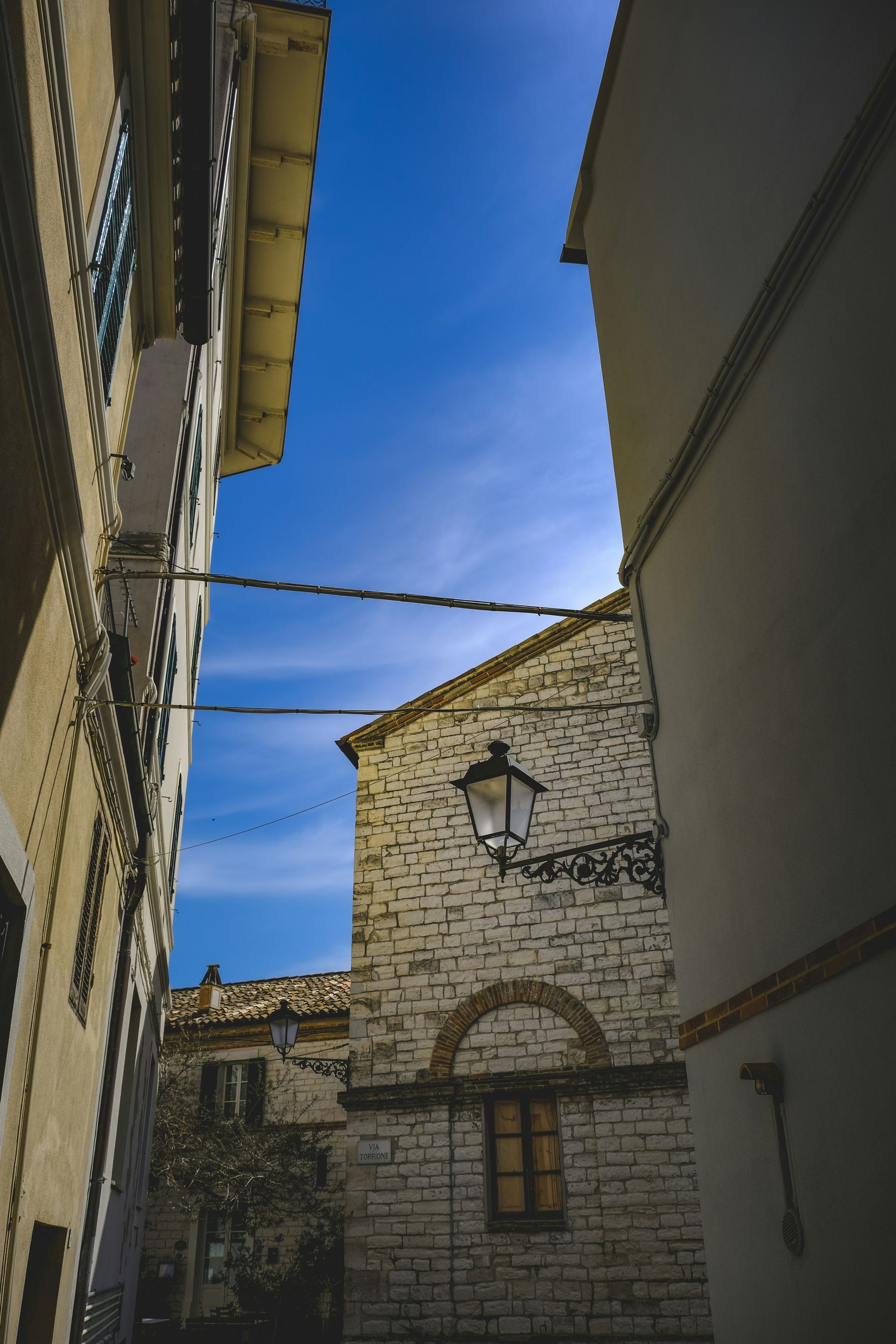A narrow alleyway between two buildings with a blue sky in the background in Sirolo, Italy