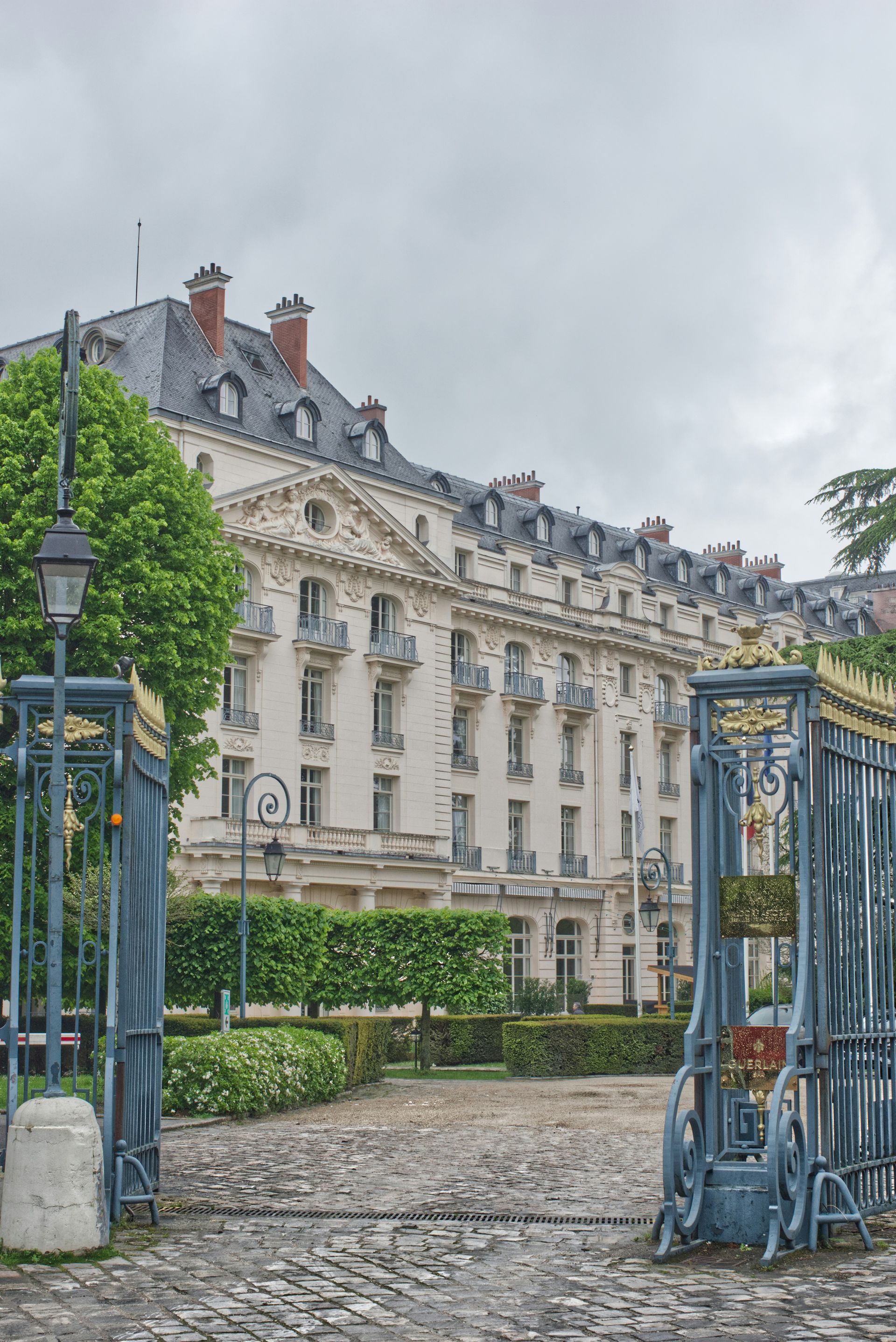 A large white building with a blue gate in front of it at the Palace of Versailles in France.