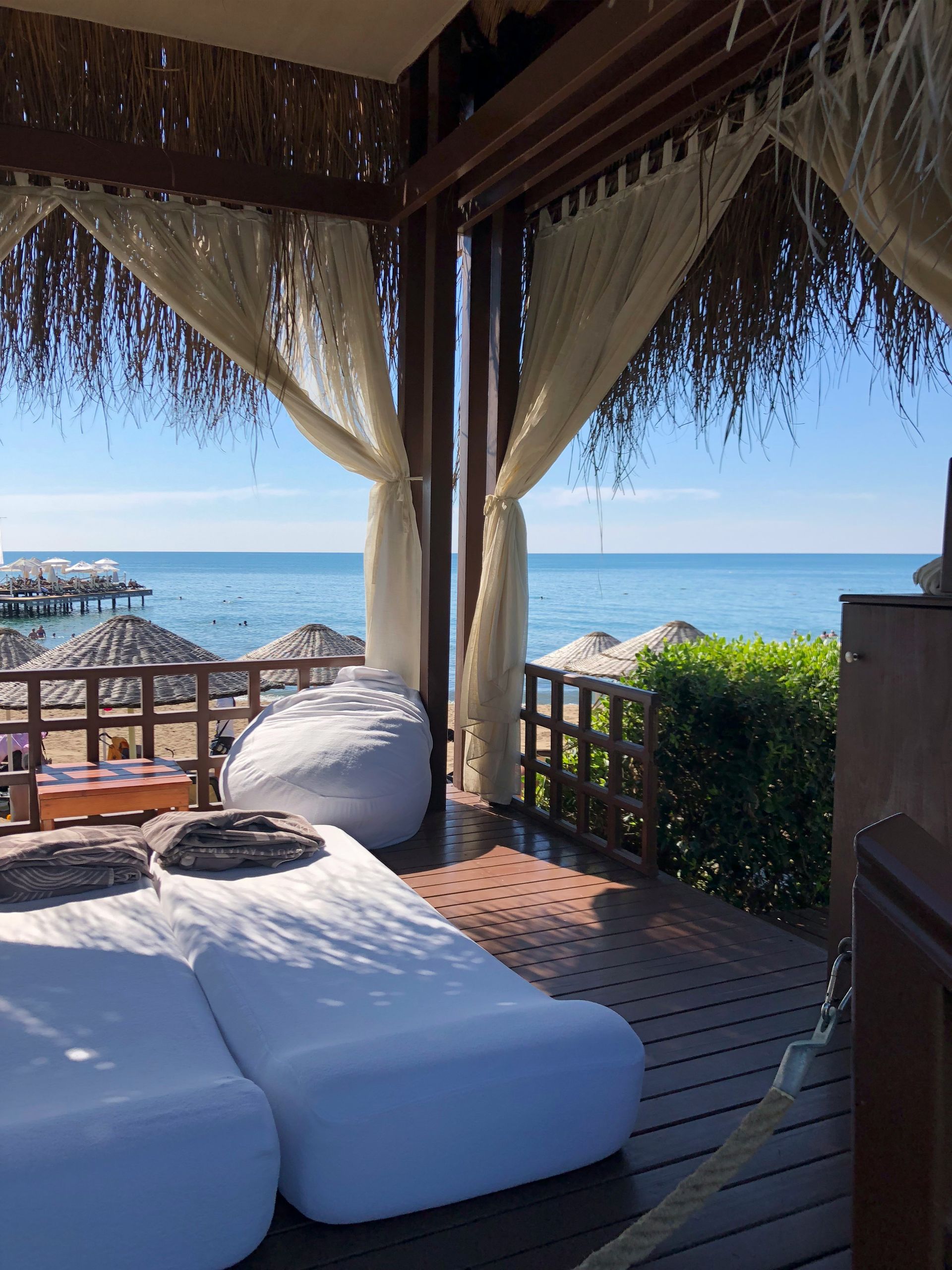 A beach cabana with white daybeds, overlooking the ocean in Antalya, Turkey.