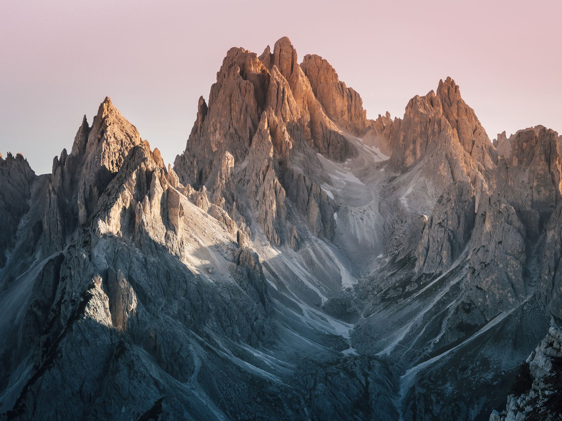 The Dolomites with a pink sky in the background in Italy.