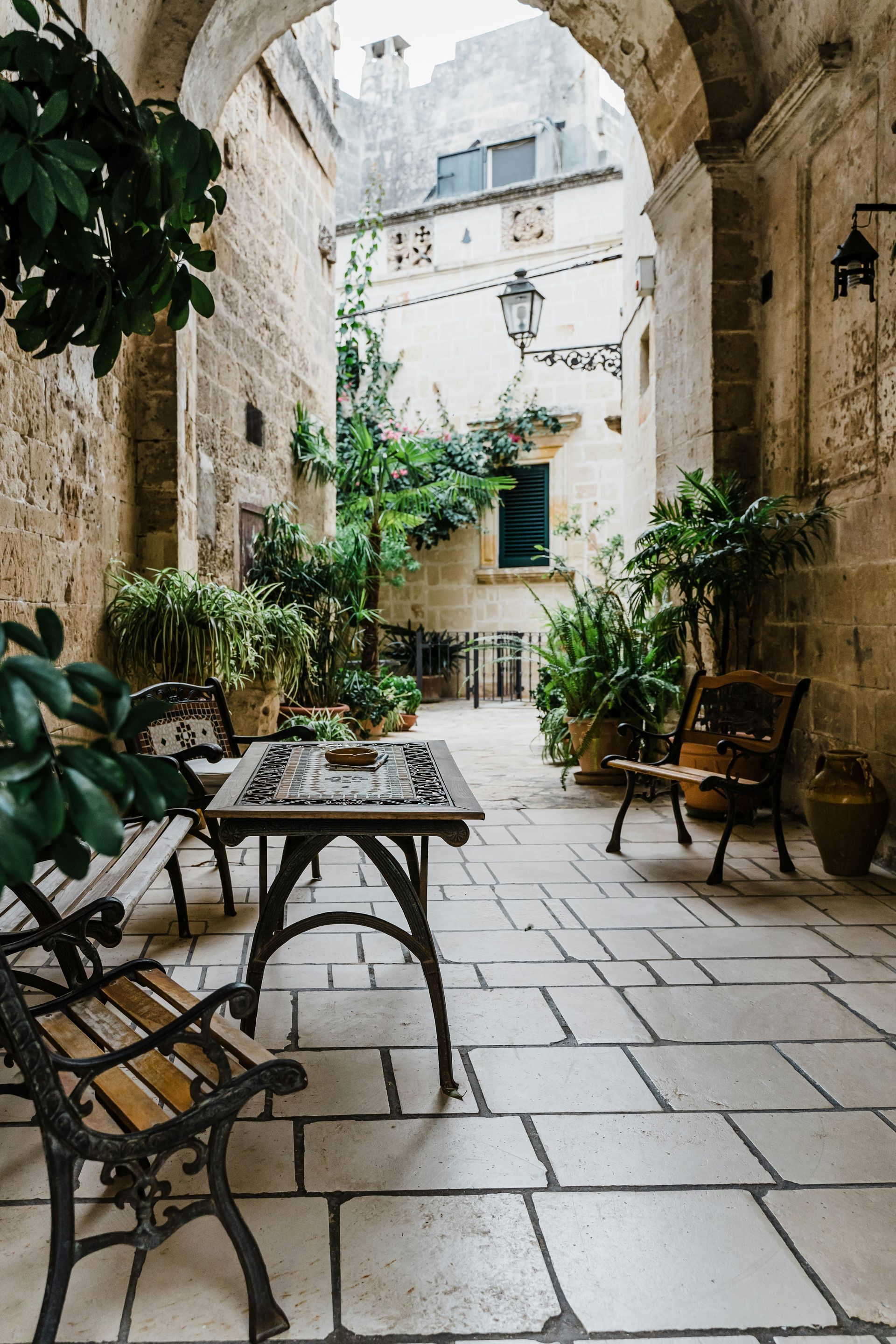 There is a table and chairs in the middle of the courtyard in Puglia, Italy.